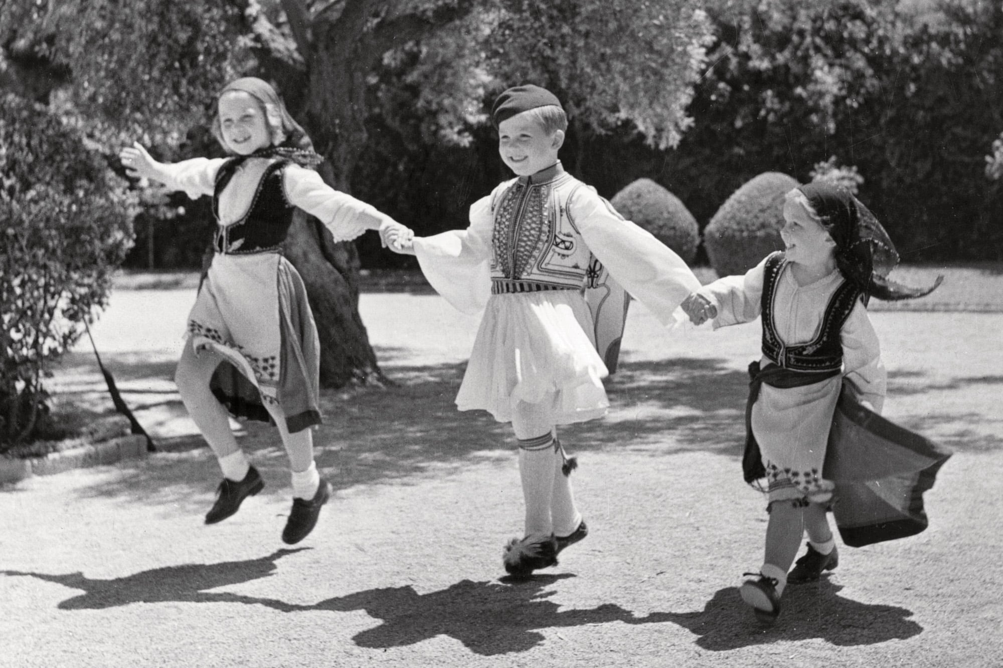 Junto a sus dos hermanos (con trajes típicos griegos), bailando en los jardines de su casa en Psychiko, en Grecia, en 1947. Irina es la chiquita de la derecha