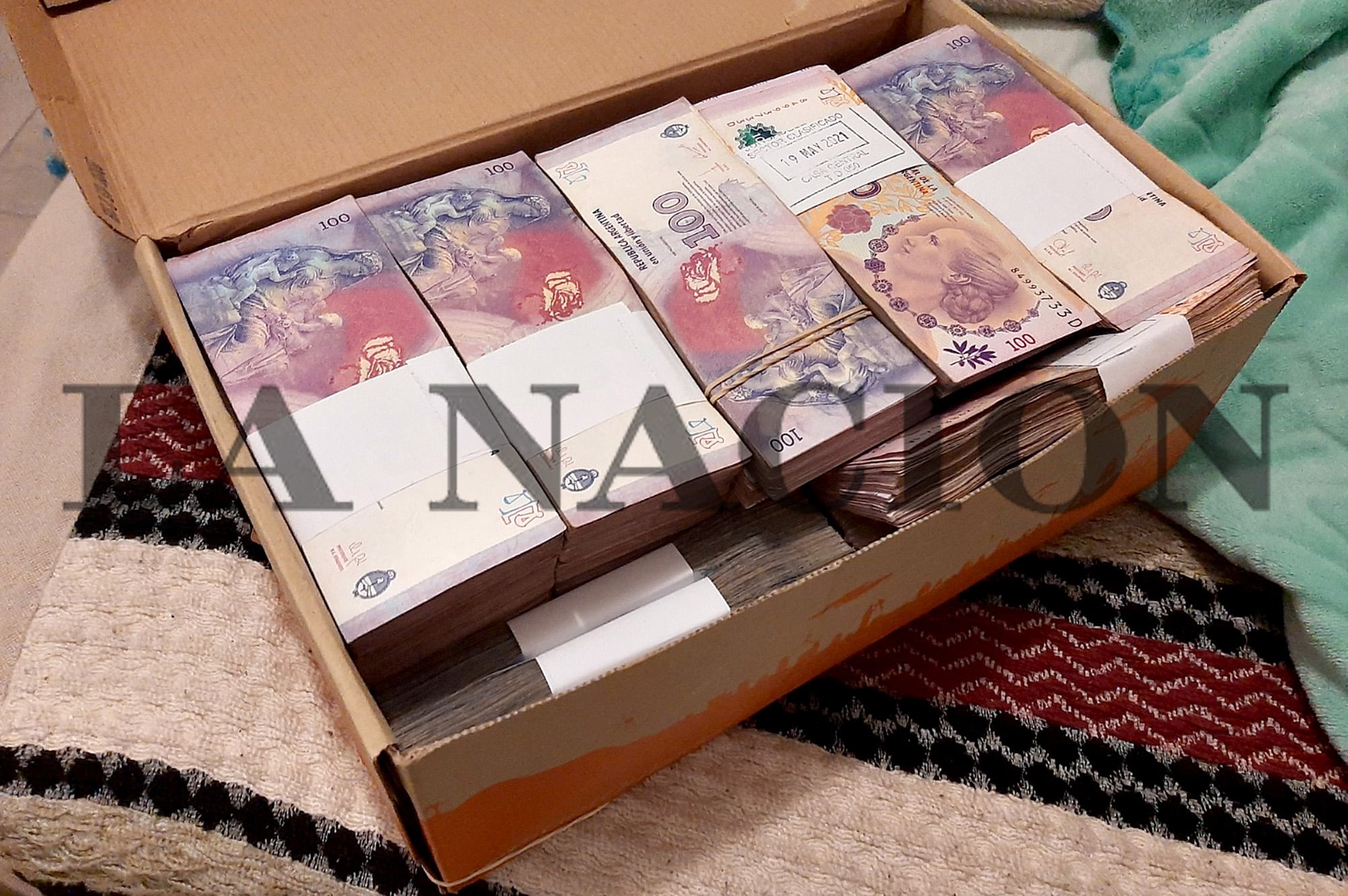 Una entrega de dinero en pesos, que lleva un cartel con un sello que dice