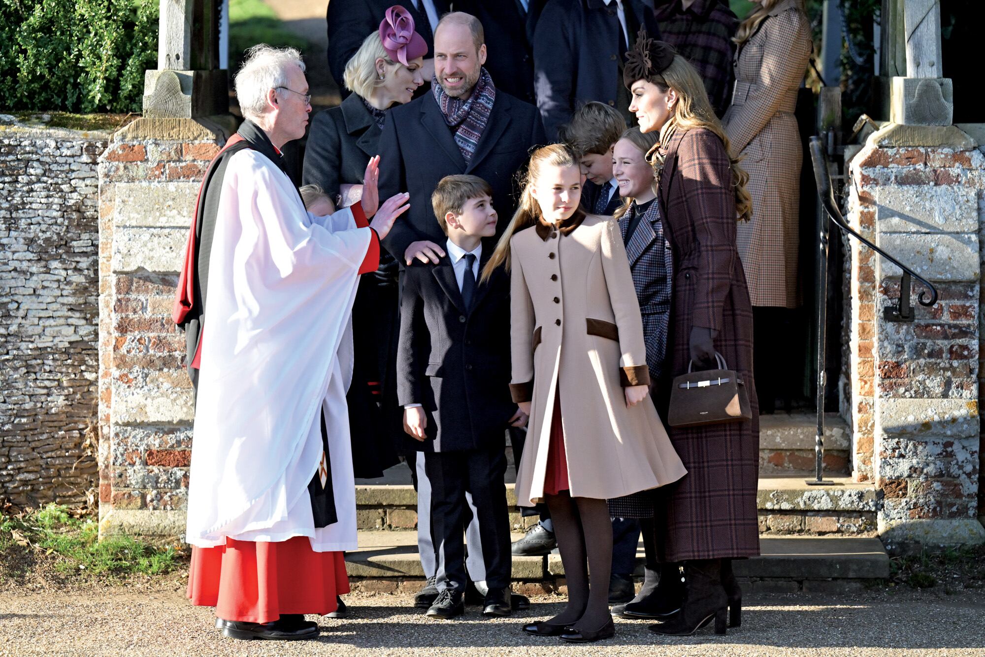 Los príncipes de Gales, William y Kate, junto a sus hijos George, Charlotte y Louis, quienes fueron recibidos por el reverendo Paul Rhys Williams. Junto a ellos se encuentra Mia, la hija de Zara Phillips y Mike Tindall