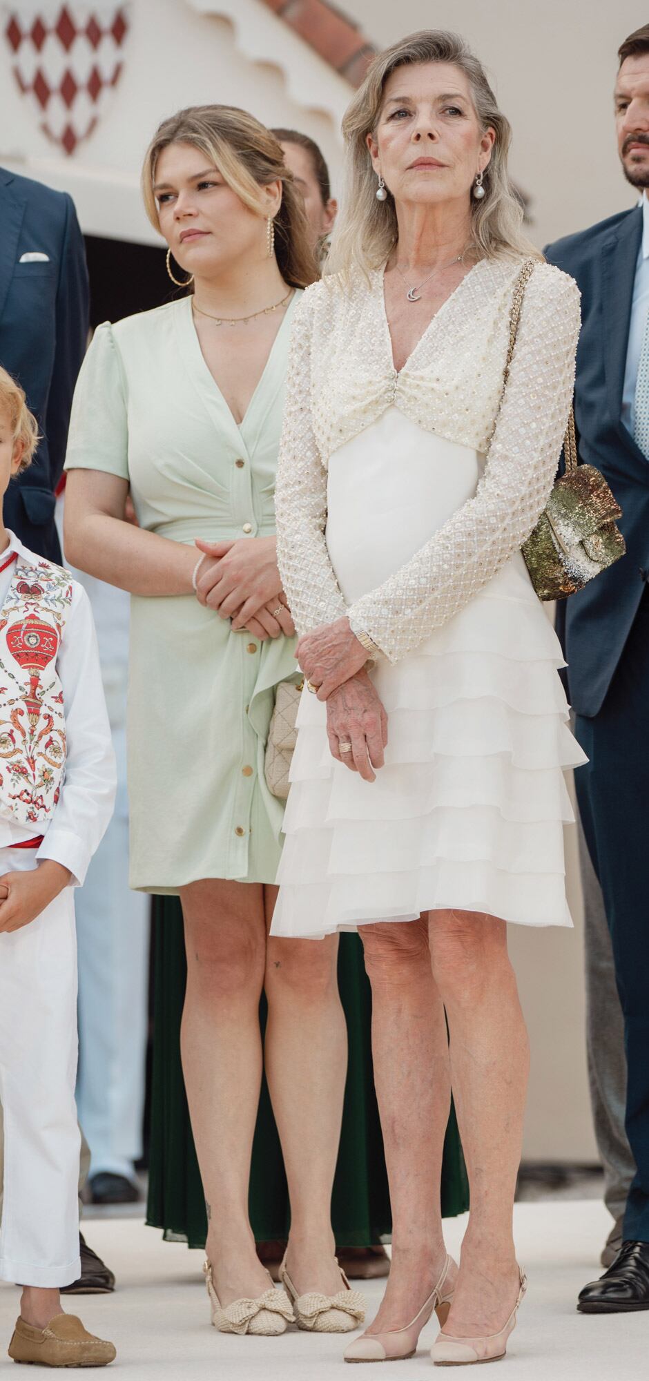Para esta ocasión, la princesa Carolina llevó un look formado por dos piezas de alta costura de la colección primavera-verano 2022 de Chanel, su etiqueta de cabecera: un vestido de seda con finos breteles y volados y un bolero con brillos. Acompañó el conjunto con stilettos bicolor y cartera también de Chanel.