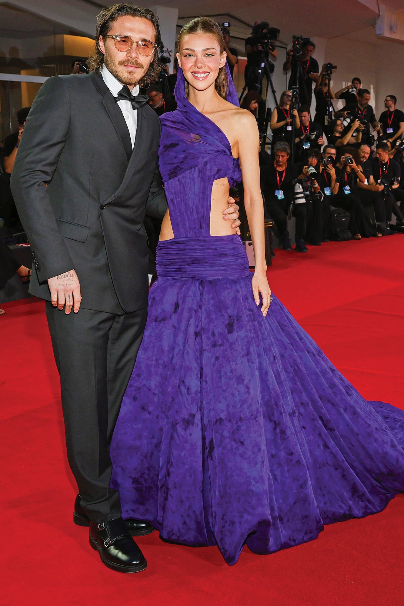 Nicola Peltz y Brooklyn Beckham asistieron a la alfombra roja de los Premios Kineo (un evento paralelo al festival). La actriz, distinguida con el premio Rising Star, lució un Balenciaga de alta costura con cortes que dejaban ver su silueta. Él eligió un smoking clásico
