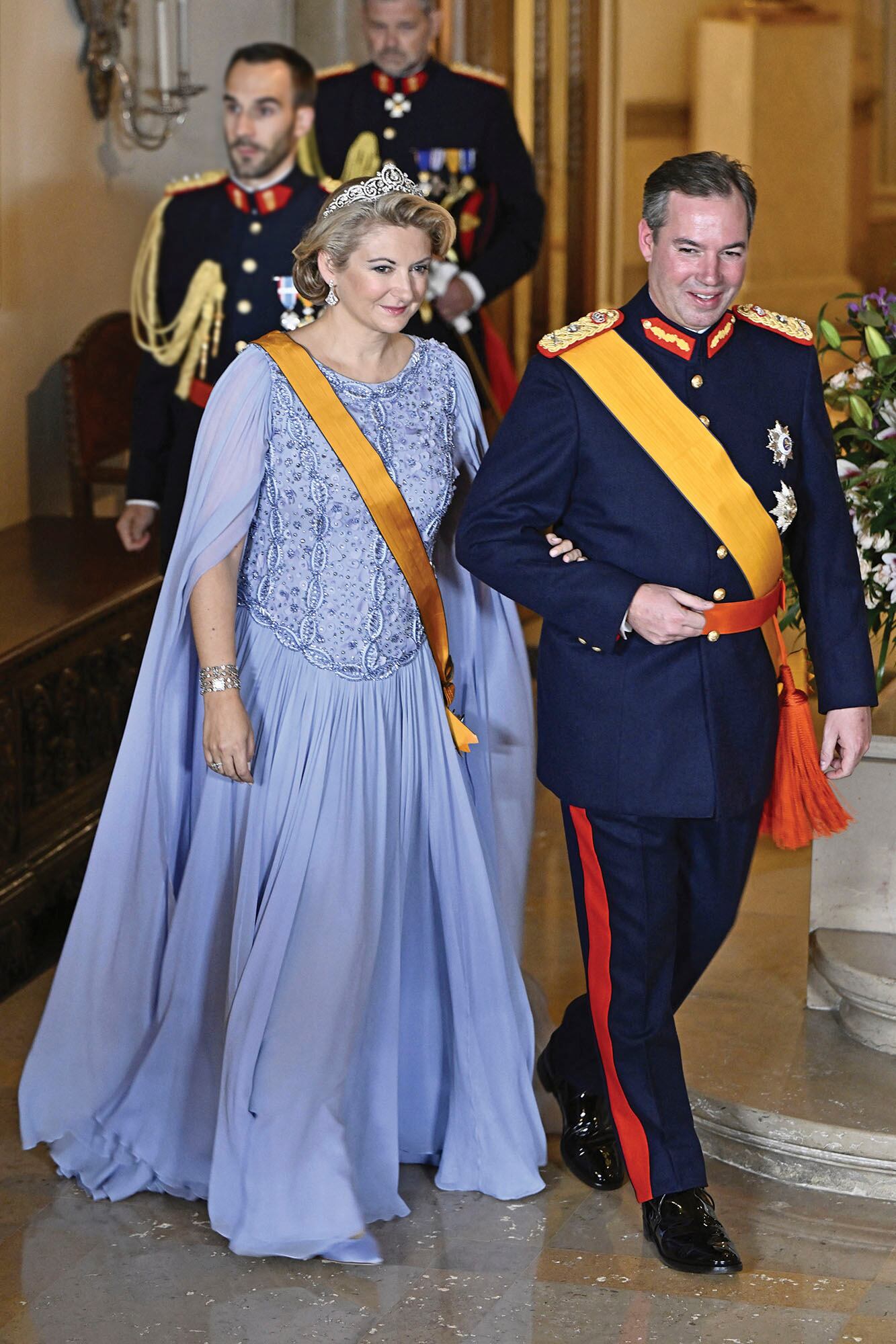 Los Grandes Duques Guillermo y Stéphanie, listos para recibir a sus invitados. Ella vistió un diseño de Elie Saab con cuerpo bordado en pedrería, falda de gasa plisada y capa (es el mismo traje que llevó por la mañana, durante la ceremonia de entronización), y la tiara belga de pergamino, una pieza que la Gran Duquesa Josefina recibió como regalo de boda, en 1954