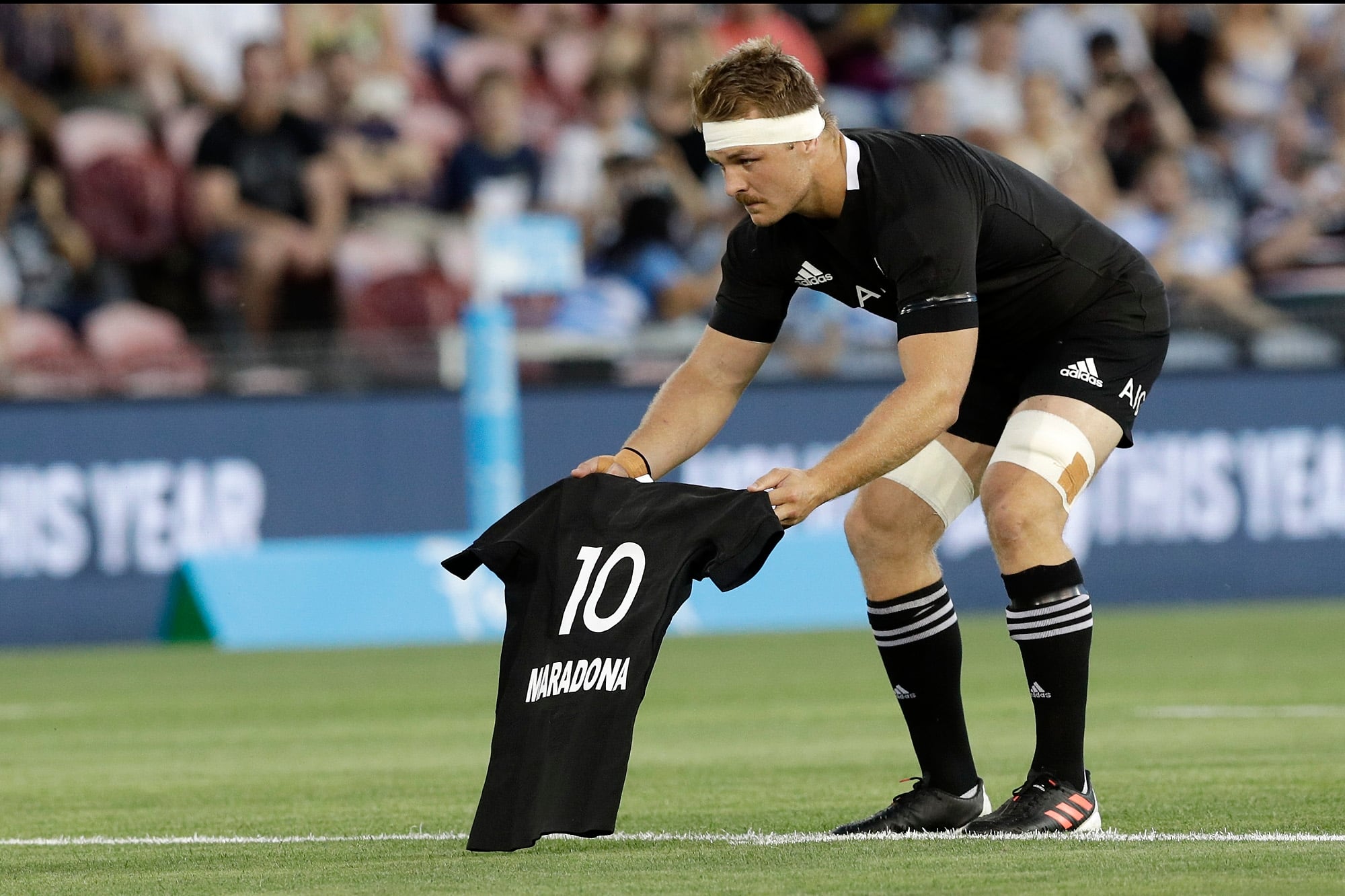 El capitán de los All Blacks, Sam Cane, ofrendando una camiseta negra con el nombre de Maradona antes del partido frente a los Pumas