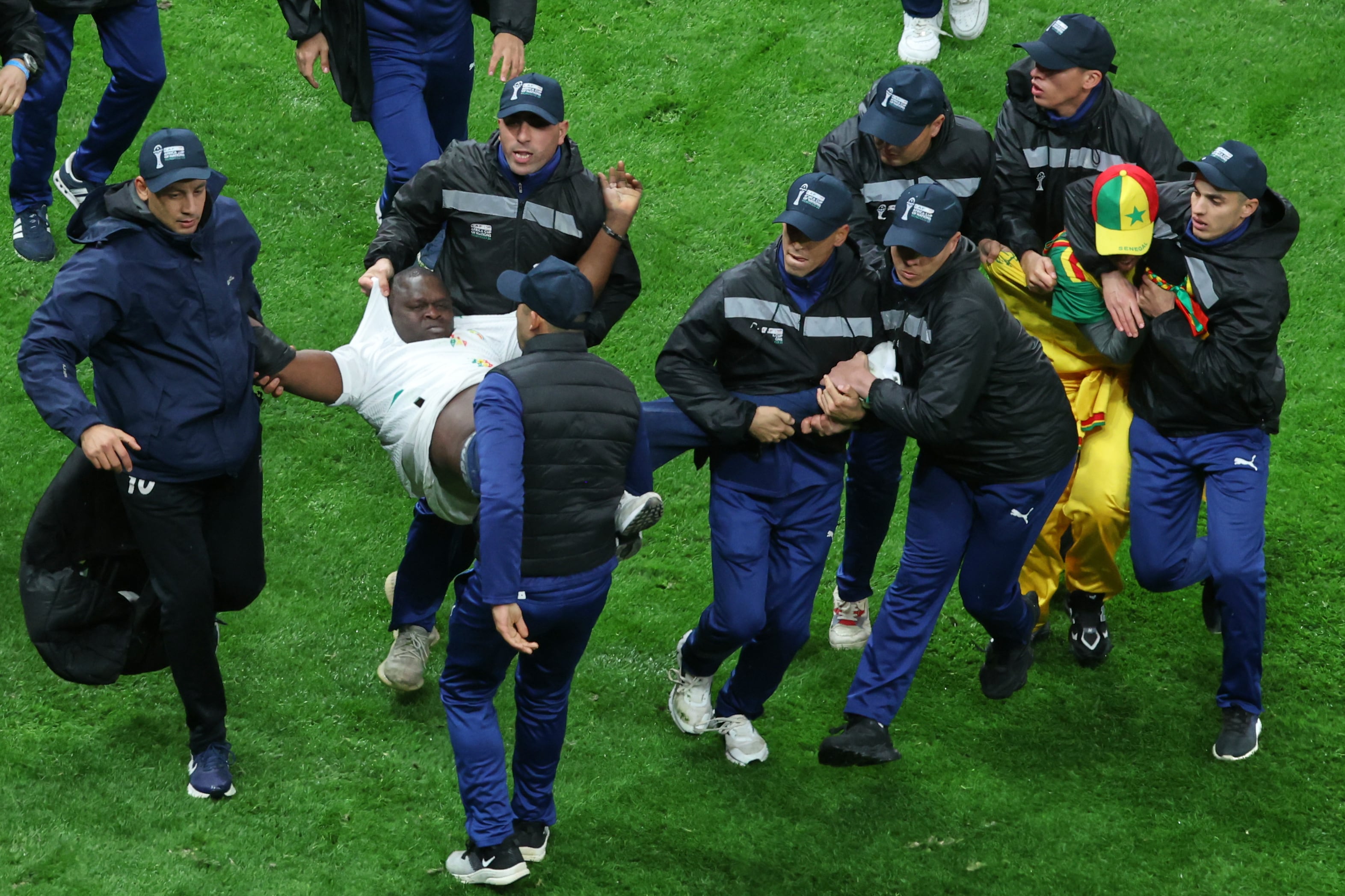 Hinchas de Senegal son sacados de la cancha durante la final de la Copa Africana de Naciones contra Marruecos, el domingo 18 de enero de 2026, en Rabat. (AP Foto/Youssef Loulidi)