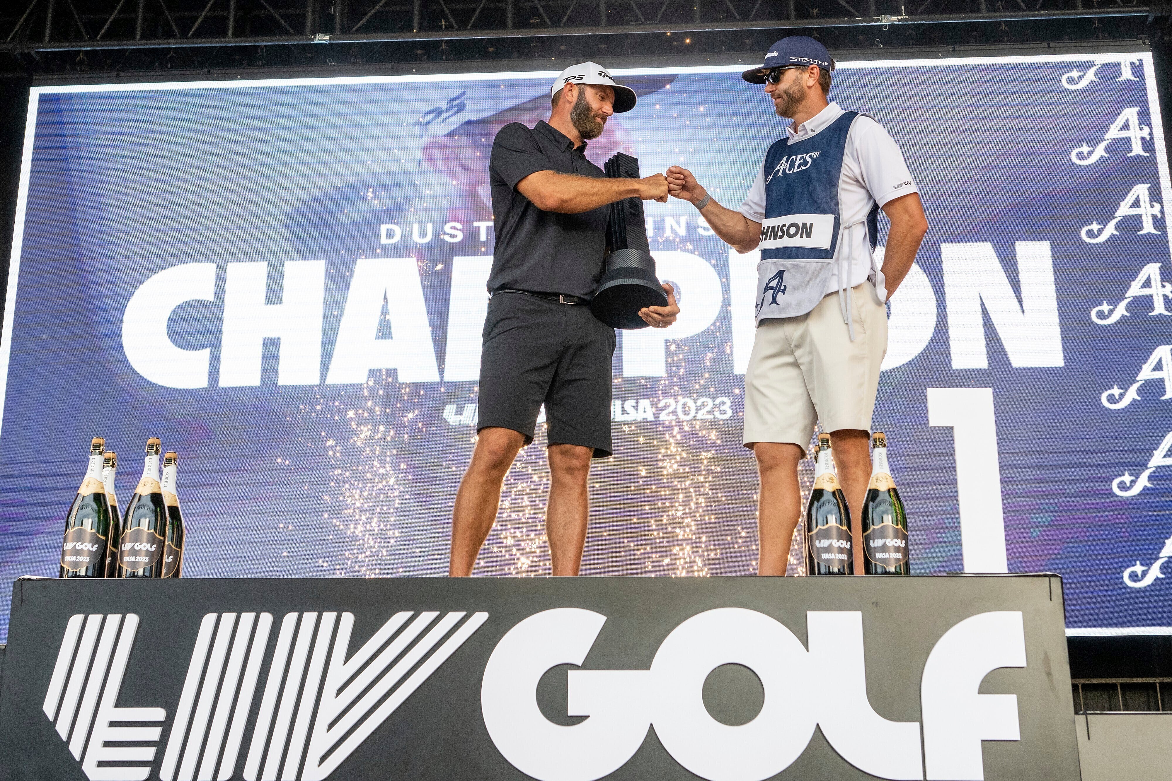 En foto del 14 de mayo del 2023, l campeón individual Dustin Johnson y su caddie Austin Johnson celebra en el podio durante la ceremonia de trofeo en el torneo LIV Golfen el Cedar Ridge Country Club de Tulsa