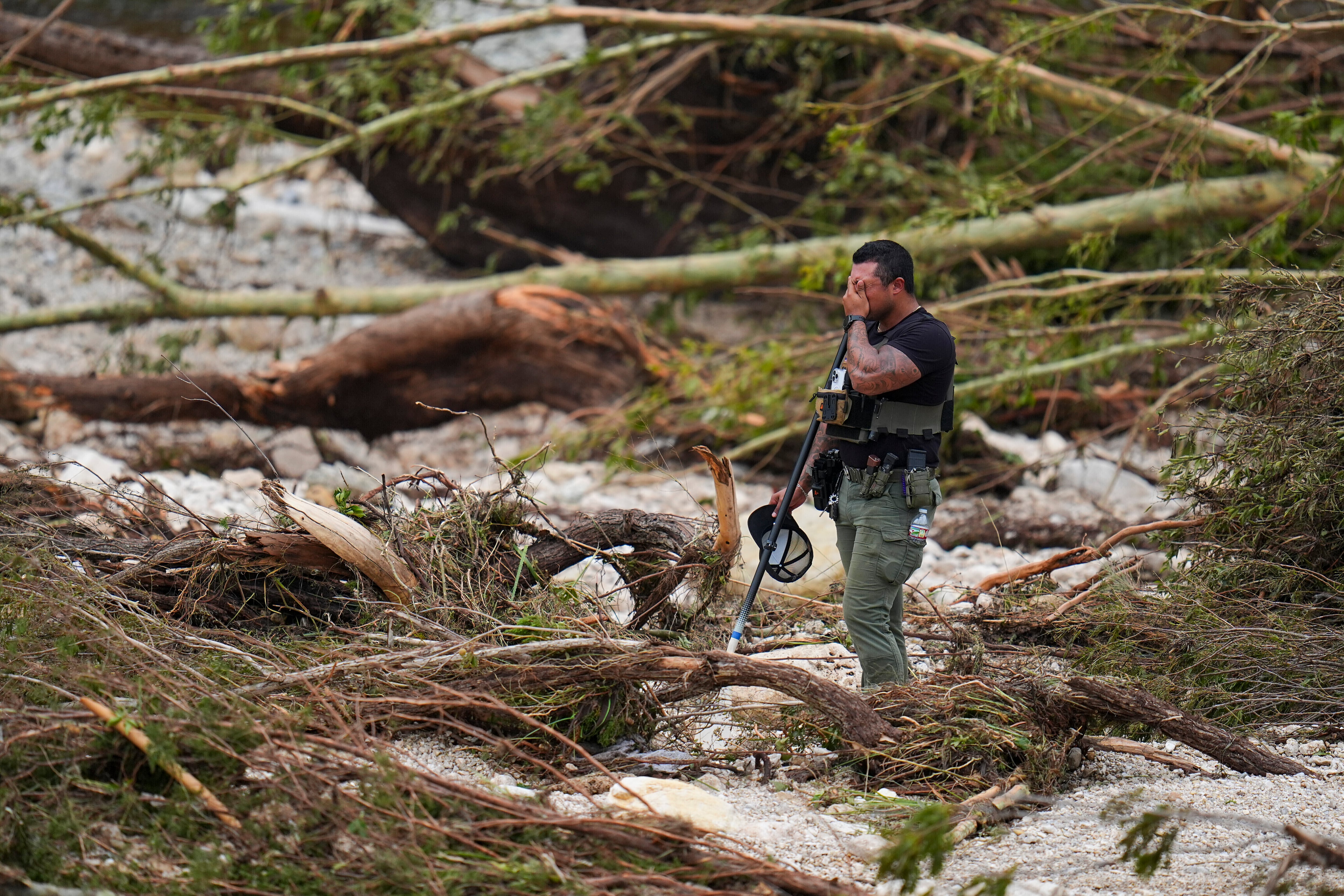 Un agente de la policía del condado hace una pausa mientras busca en las orillas del río Guadalupe cerca de Camp Mystic, tras una inundación repentina en la zona, el sábado 5 de julio de 2025, en Hunt, Texas. (AP Foto/Julio Cortez)