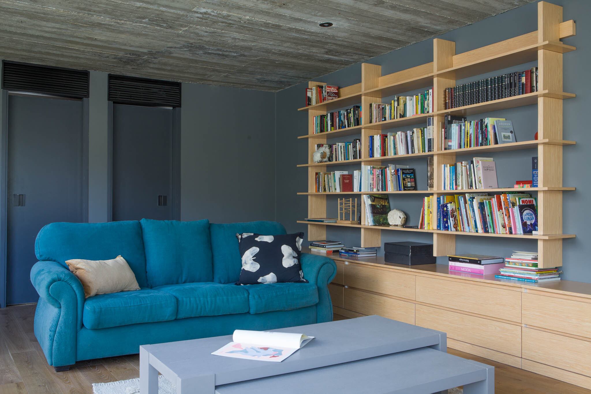 Sillón vintage retapizado en pana turquesa. Más atrás las puertas a los dormitorios