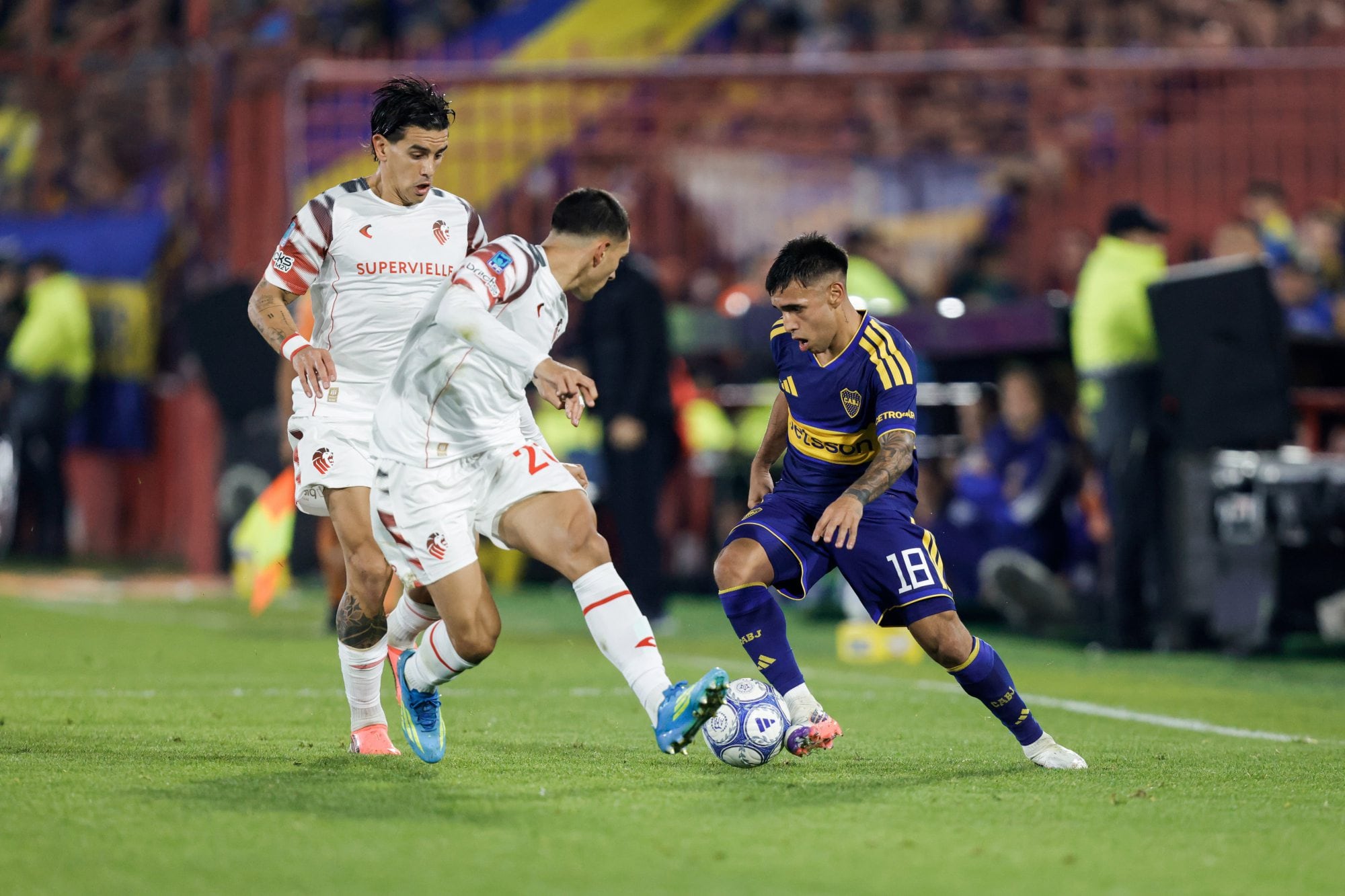 Miltón Delgado encara con la pelota ante la marca de dos jugadores de Estudiantes