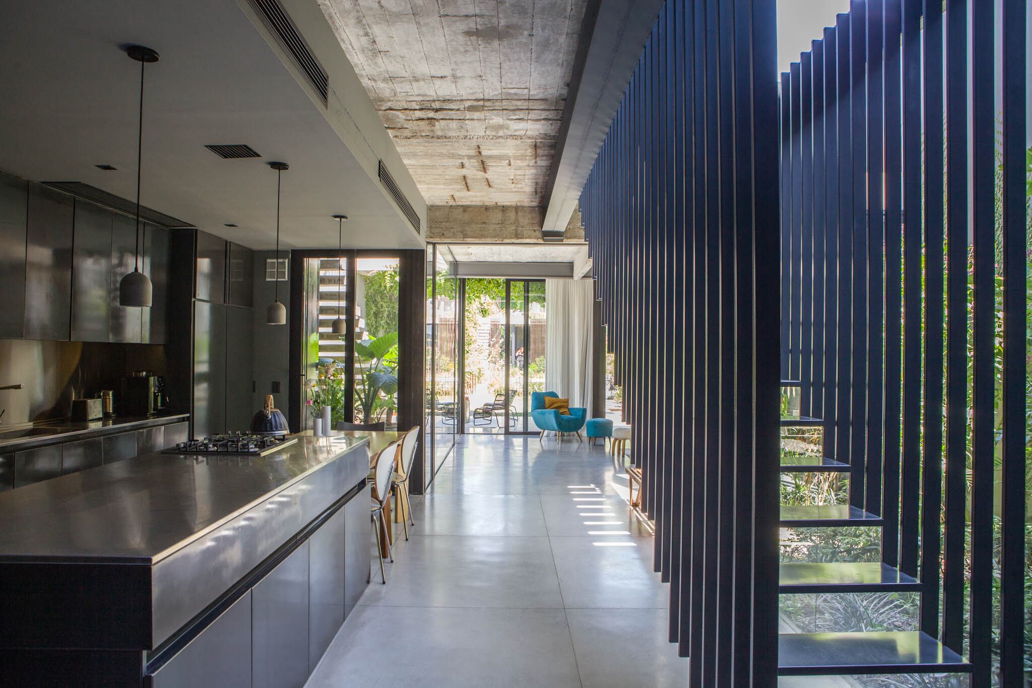 Desde la entrada, un recorrido ininterrumpido y luminoso por la cocina, el comedor diario y el living. Piso de hormigón pulido hecho en obra (Atelier M)