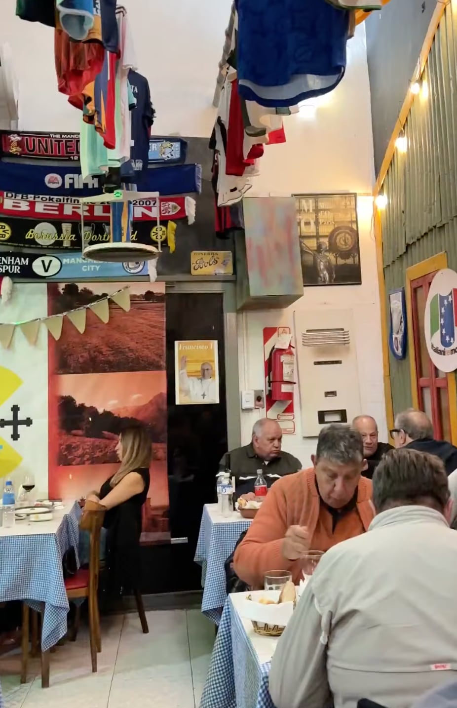 Banderines, camisetas de clubes italianos y argentinos mezclados con botellas de vino, latas antiguas, jamones colgados y carteles viejos decoran el lugar
