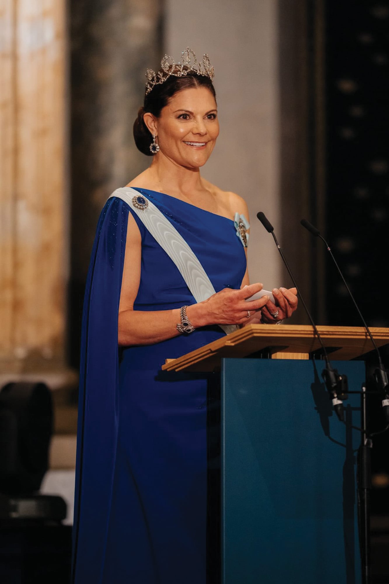 Durante el banquete, la princesa Victoria le dedicó unas palabras a su padre. Para la ocasión, la heredera eligió un diseño azul asimétrico de Christer Lindarw, con drapeado en la cintura y capa que parte del hombro y le aporta cierto aire teatral, decorado con finos bordados brillantes. Y la tiara Connaught de diamantes, con pendientes y pulsera haciendo juego