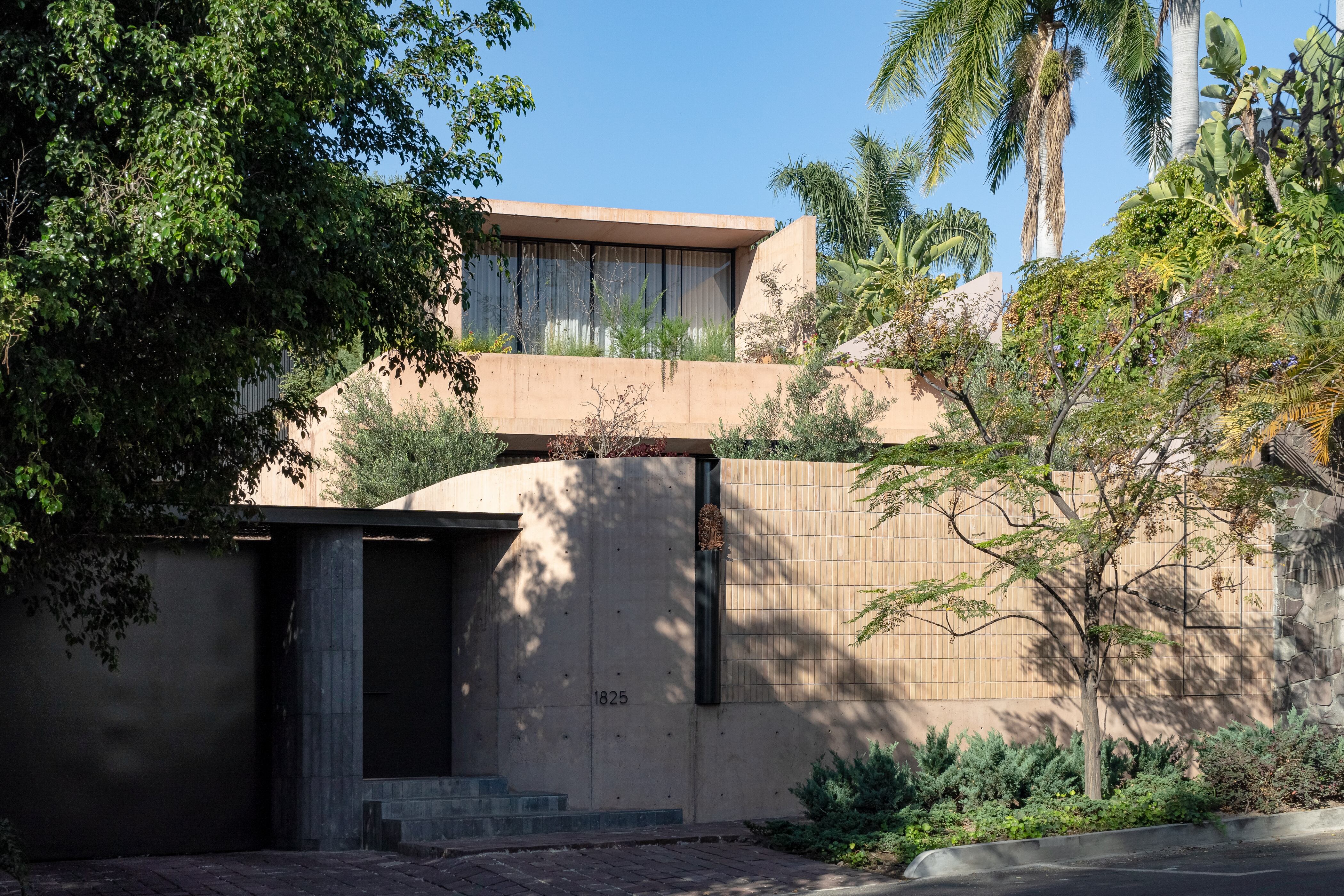 Desde la calle, un Paraíso Bolitaio y una gran jardinera en la planta superior, con jazmines y vitex, contrastan con el concreto pigmentado en tonos rosados.