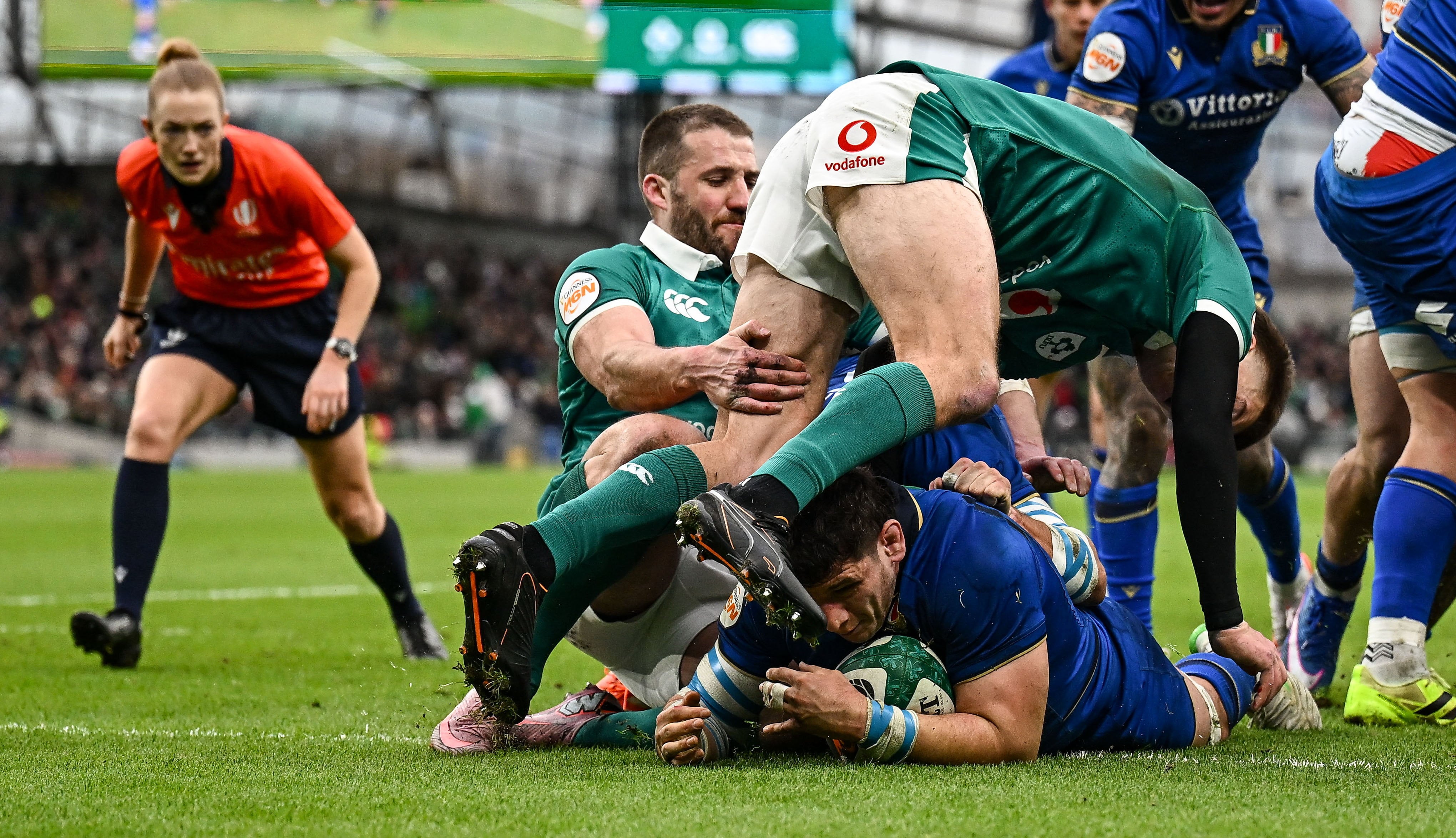 Giacomo Nicotera apoya un try para Italia ante Irlanda; de fondo, la mirada atenta de Hollie Davidson