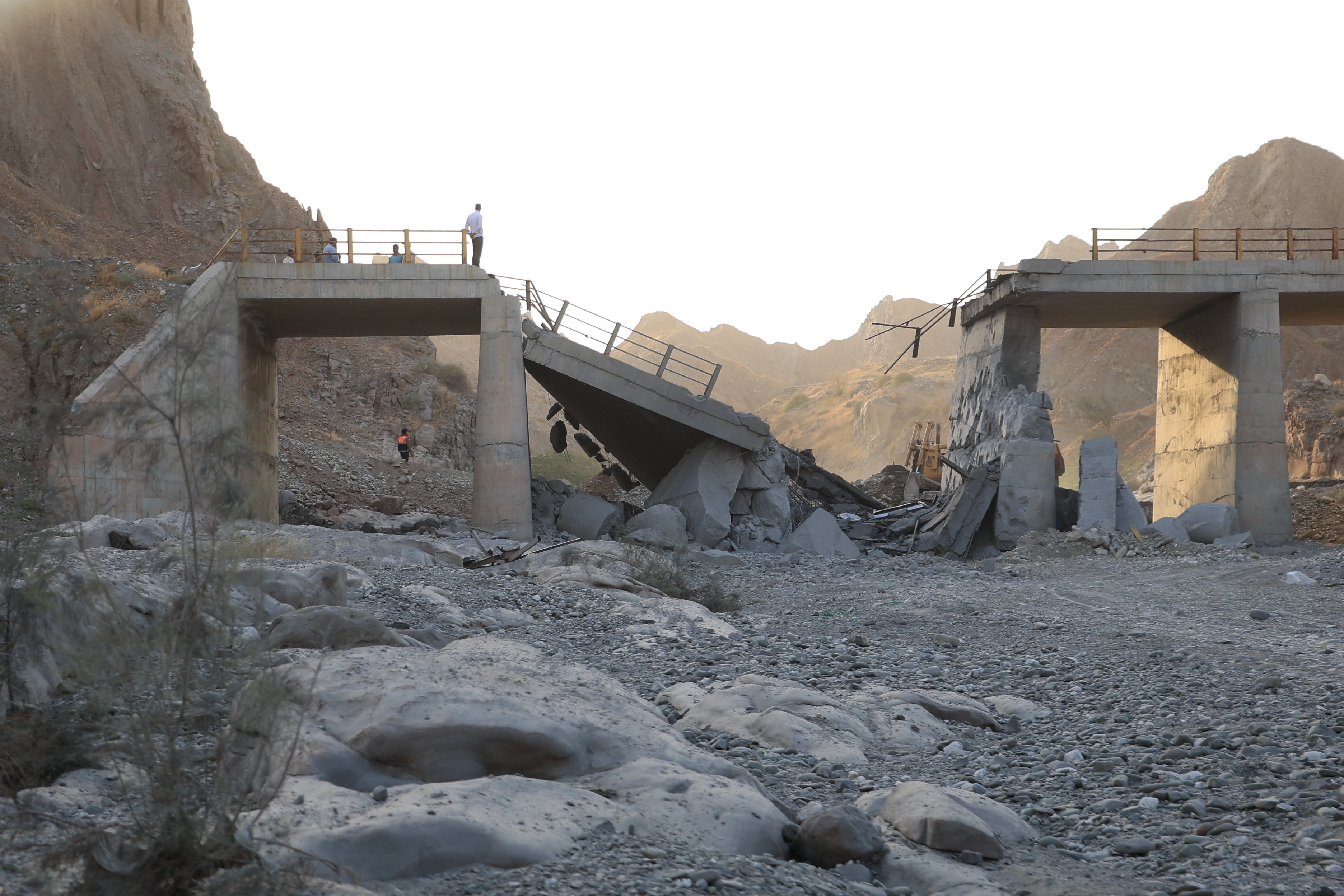 Gente de pie en un puente destruido tras un ataque en lap provincia de Hormozgan, en el sur de Irán