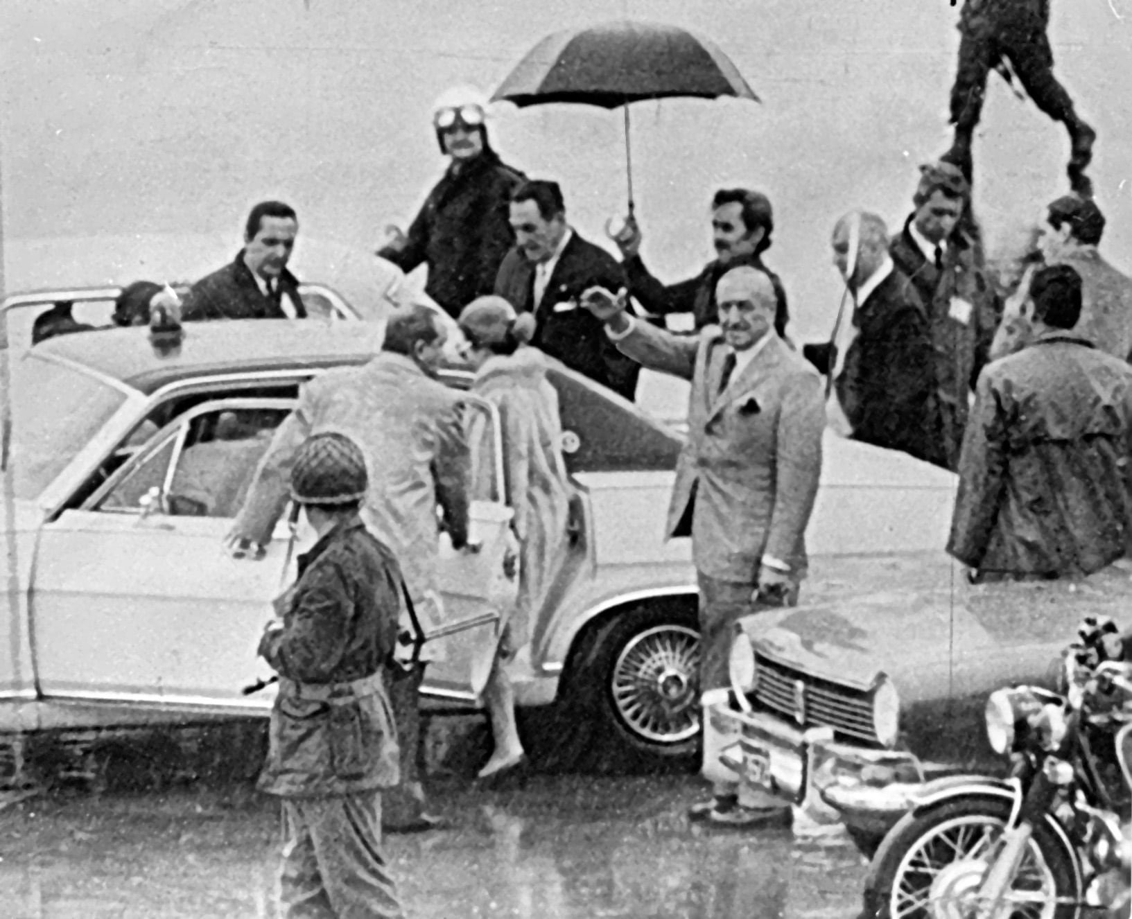 17 de noviembre de 1972. Juan Ignacio Rucci, con un paraguas, resguarda a Perón de la lluvia. Detrás de Rucci está López Rega. Mientras Isabel Perón sube al auto que los trasladará, saluda, detrás, Héctor Cámpora.