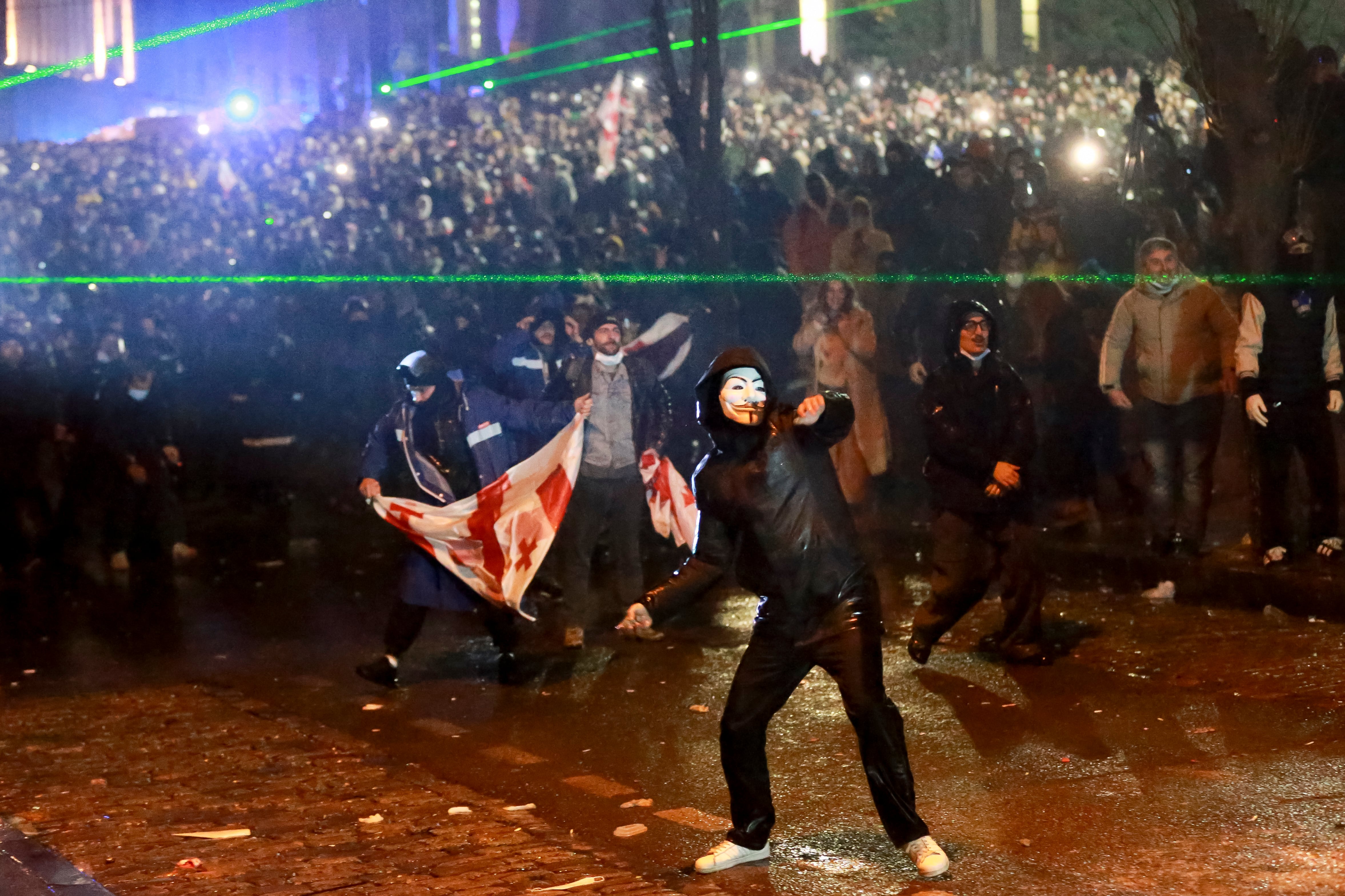 Un manifestante enmascarado lanza un objeto hacia la policía durante una protesta
