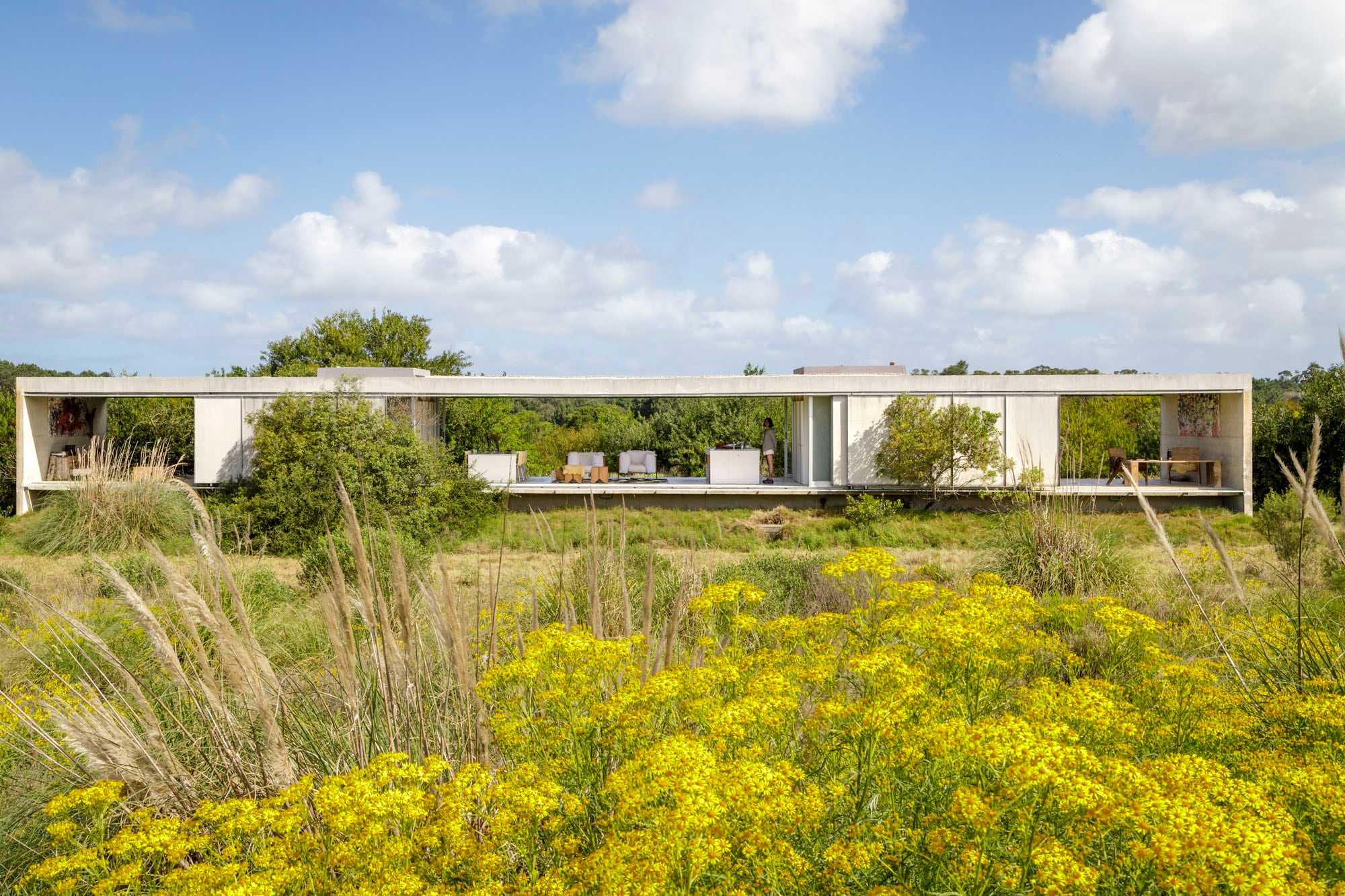 Orientada en sentido Norte–Sur para enmarcar ambos paisajes, la casa es una pieza de hormigón armado construida in situ. Al espacio social lo flanquean dos dormitorios y dos galerías.