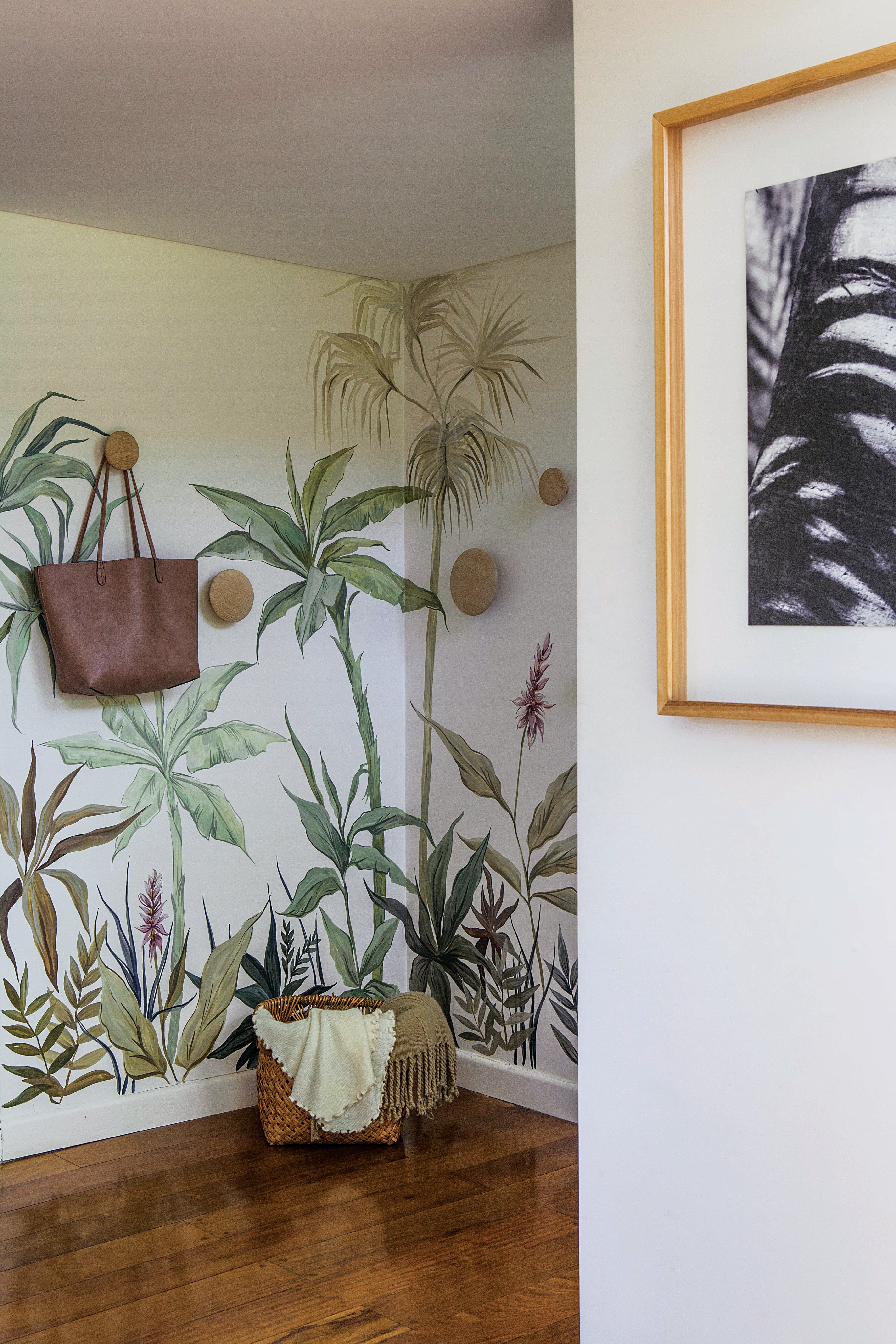 Las fotografías de Silvina (dueña de casa) se llevan a la perfección con el mural botánico de Florencia Chedufau, que le dio vida a este lugar de paso. Cuando la casa se llena de invitados, los percheros redondos (Broca Muebles) suman función al paisaje tropical.