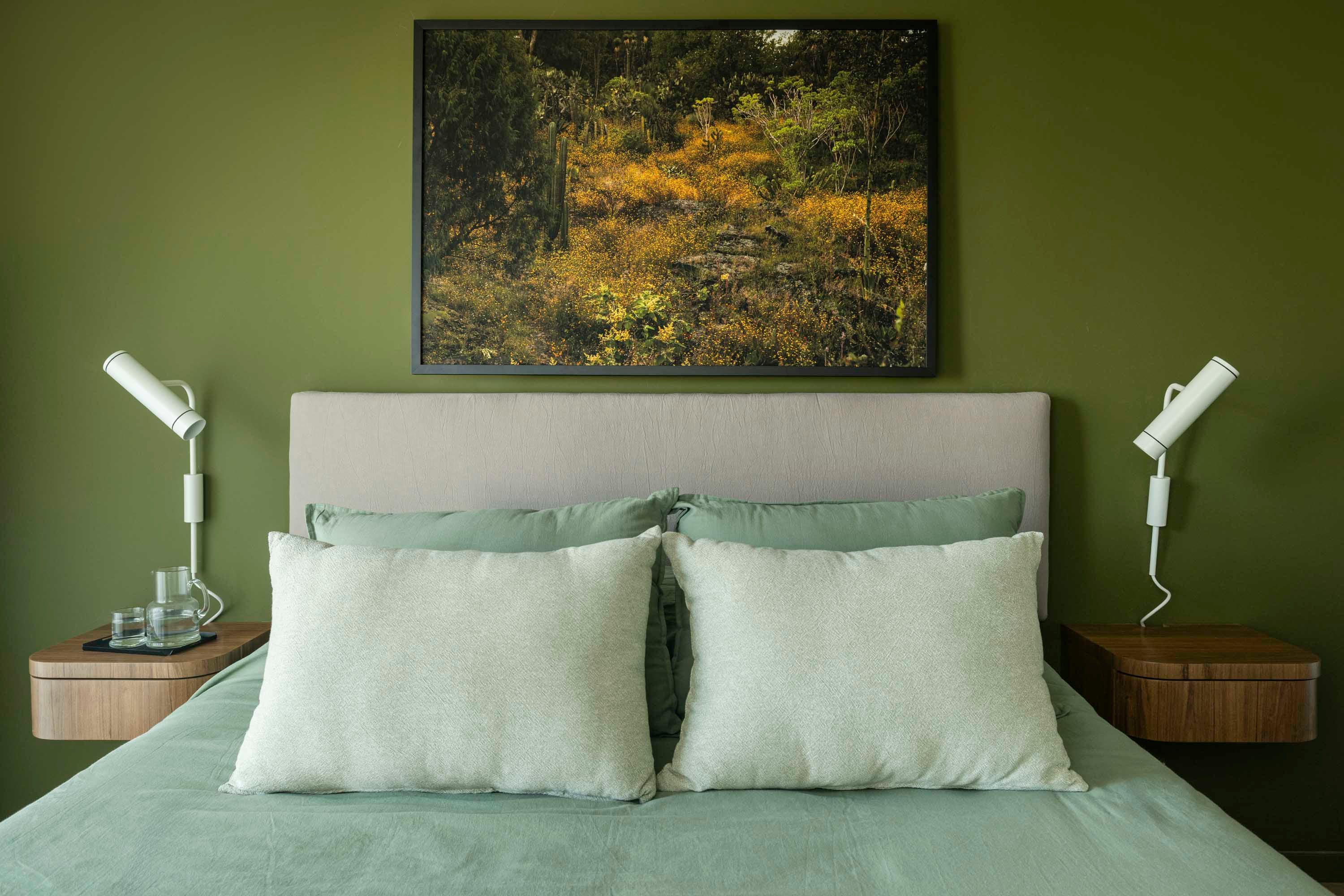 Respaldar de tusor suspendido y mesas de luz flotantes a medida enchapadas en petiribí y (Cas a Cas) con apliques amurados (Paraná 201). Pared en ‘Verde Plantación’ (Alba). Enmarcada, foto de Maia Croizet.