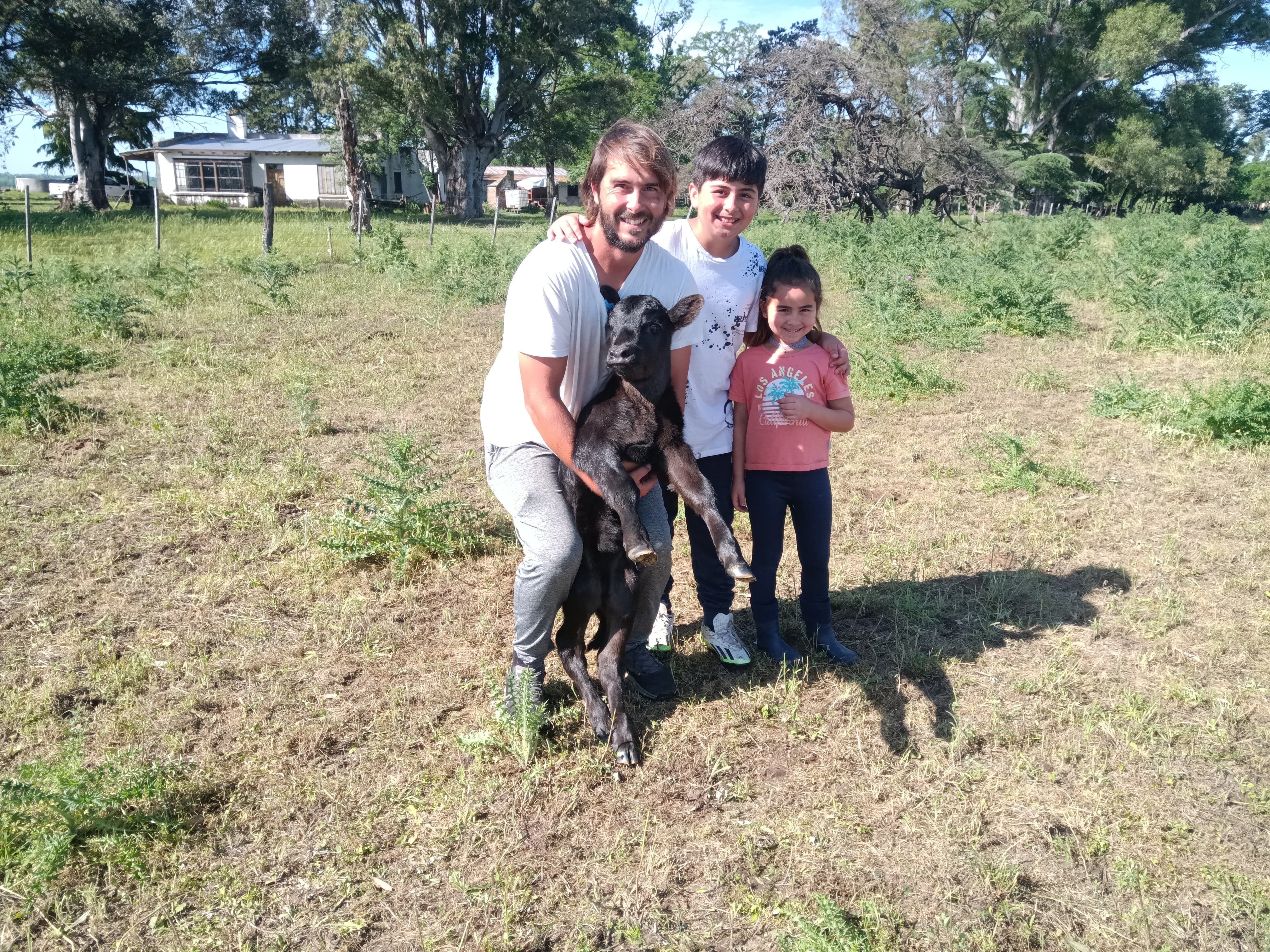 Santiago Malano sonríe en el campo junto a dos de sus tres hijos