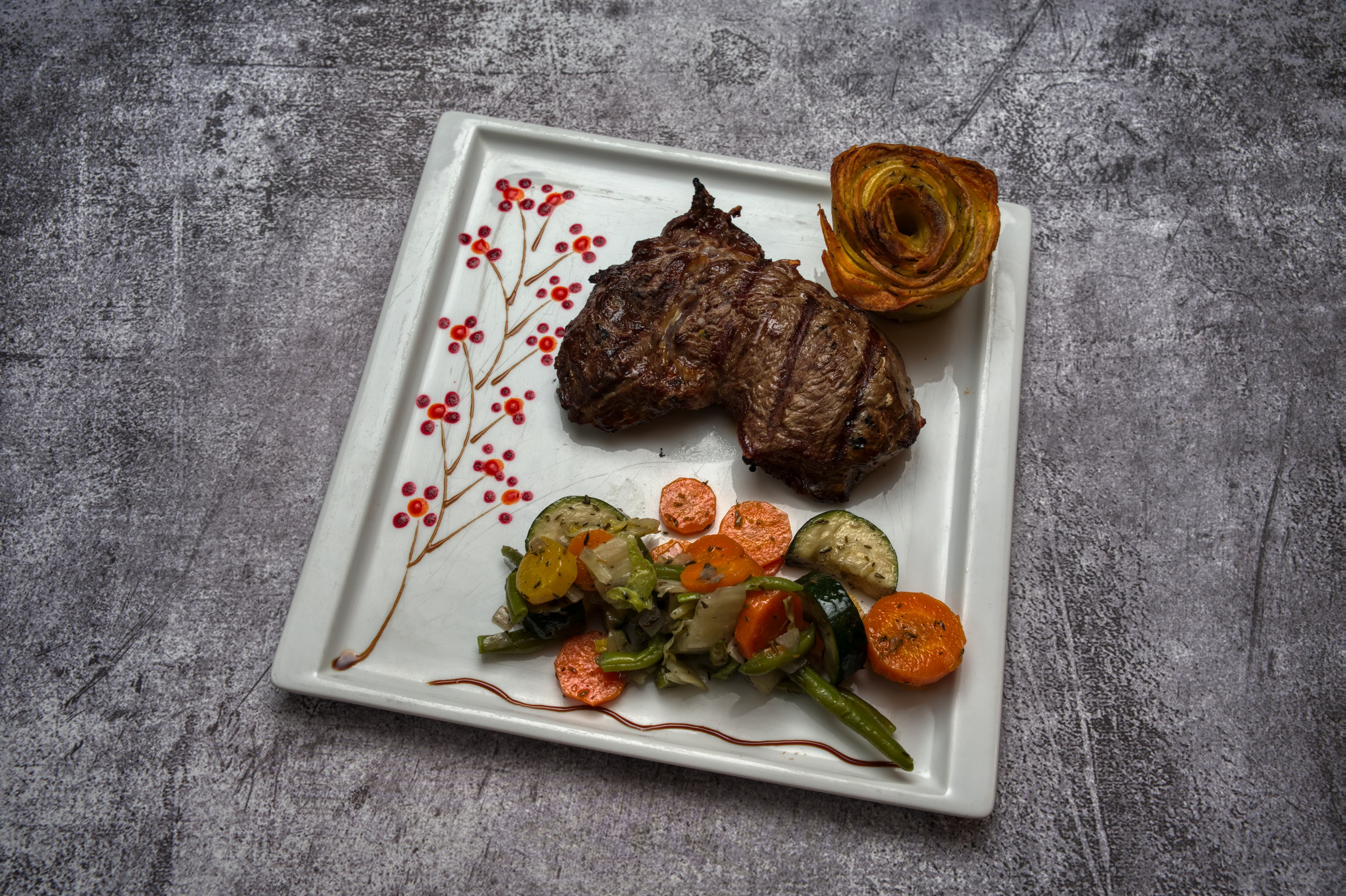 Entrecote acompañado de vegetales salteados y una flor de papa crocante