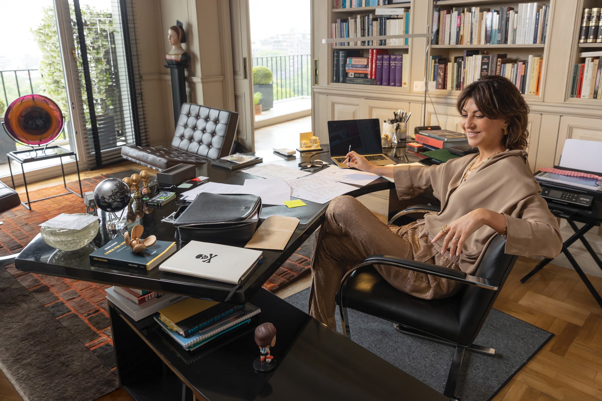 En el escritorio de la casa, rodeada de sus libros favoritos y de sus apuntes de italiano: hasta hace no mucho, Eva estudiaba canto, ahora toma clases de italiano. Acá, luciendo una camisa de crêpe de seda natural doble y un pantalón con cristales austríacos termoadheridos sobre crêpe de seda