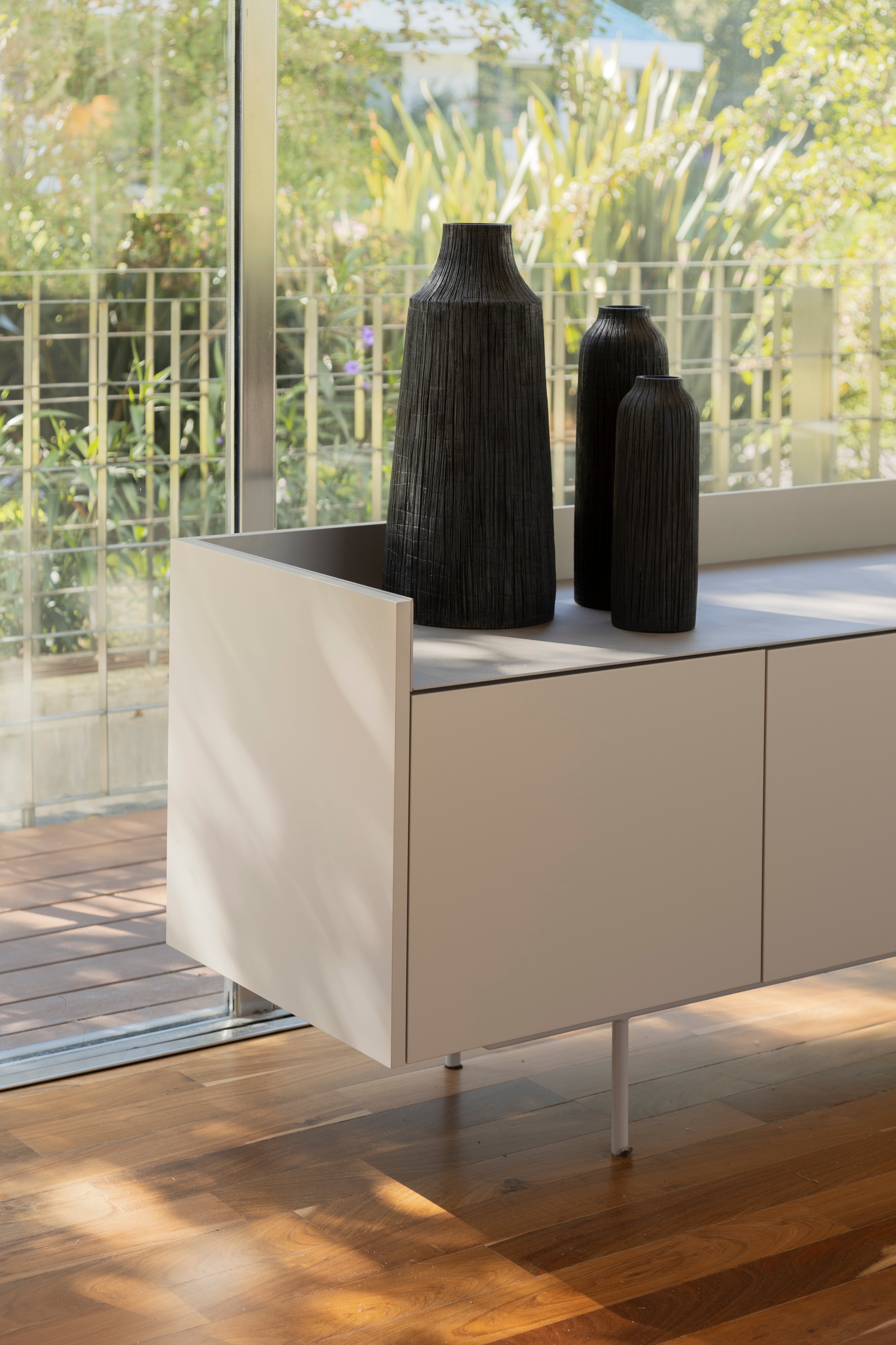 Convocaron al estudio que había hecho su casa para renovarla 10 años después 14 El mueble de la TV también es bar, hecho de madera laqueada con lustre semimate (Sherwin-Williams) y estructura metálica en el mismo tono. Jarrones (Andy Forn Casa).