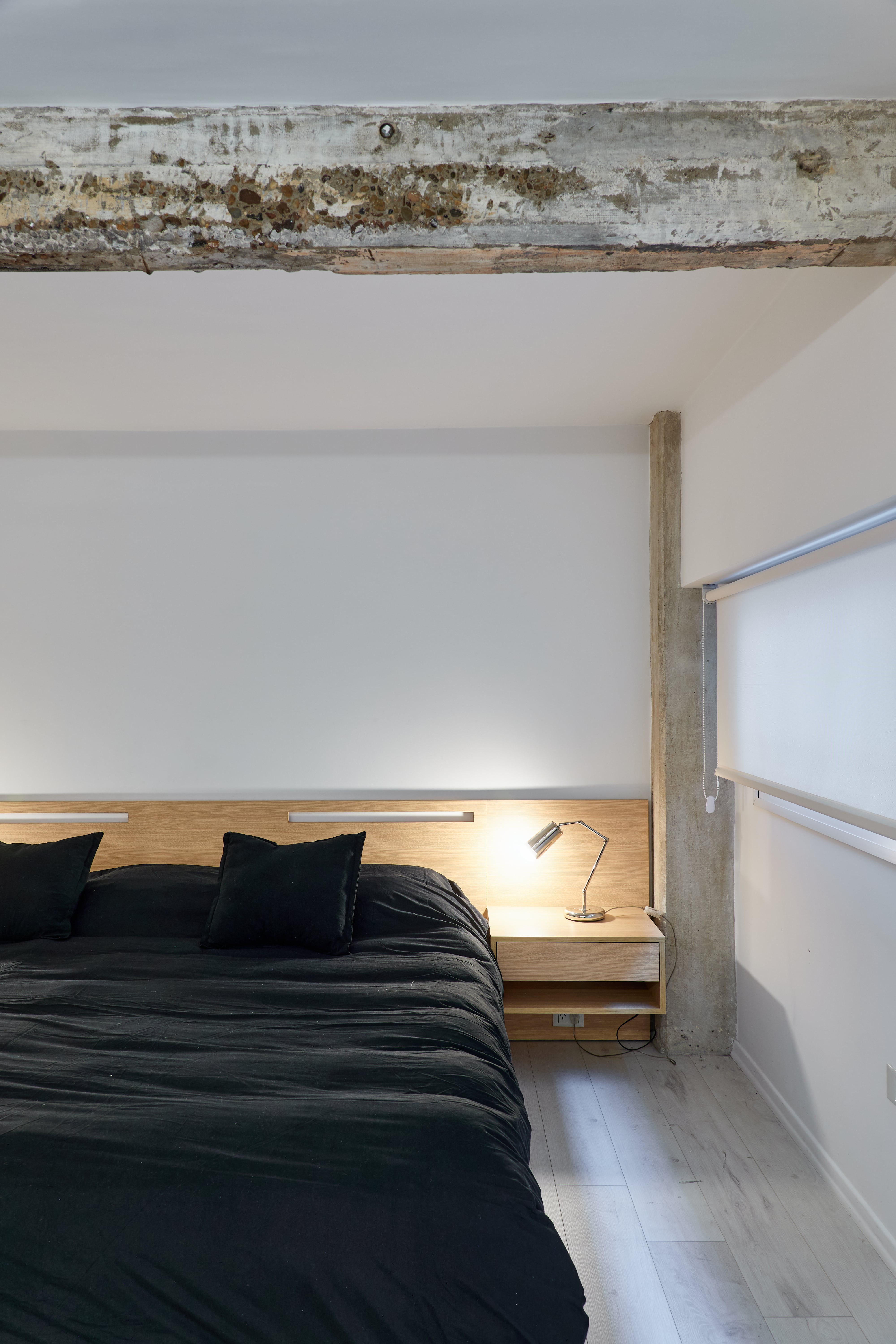 Cabecera y mesas de noche enchapadas en guatambú (Wollstudio). Para todas las ventanas del loft eligieron cortinas black out blancas.