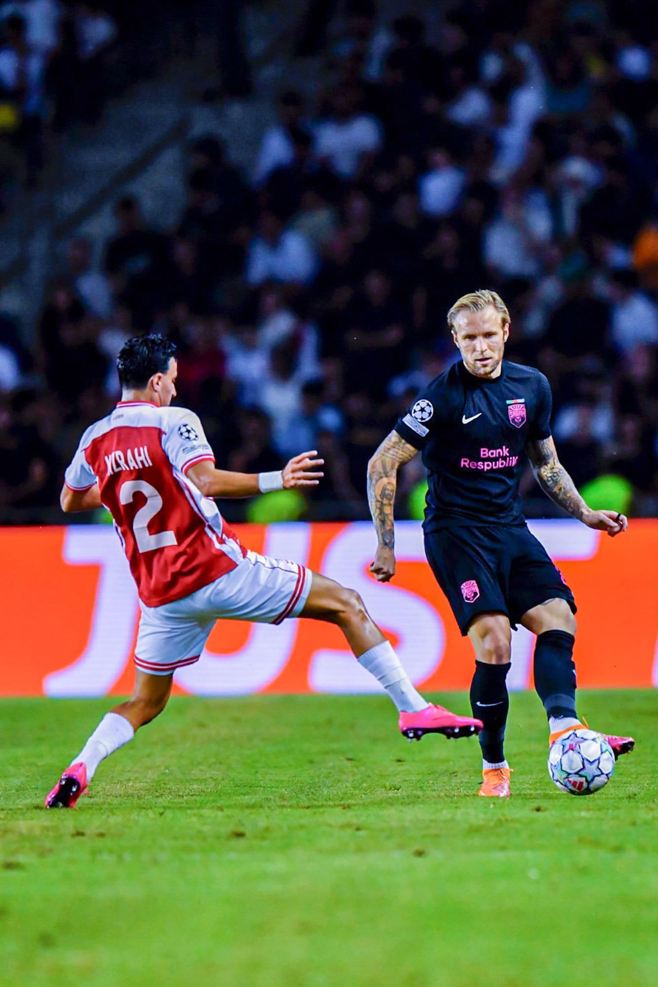 Tymoteusz Puchacz, de Sabah FK, pasa la pelota ante la marca de Guy Mizrahi, de Hapoel Beer Sheva