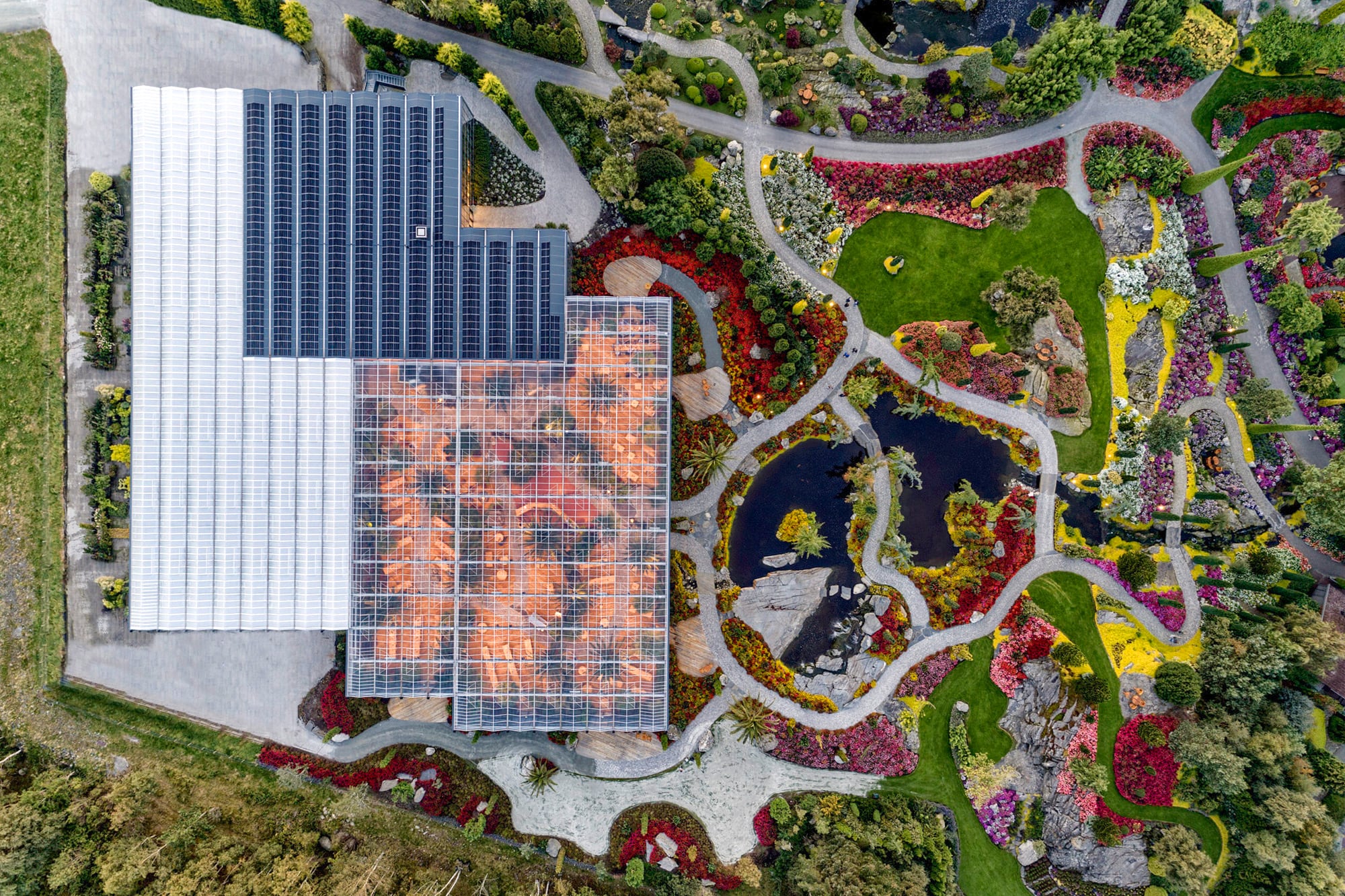 Plano con vista superior del invernadero, con sus paneles solares y el paisaje con todos los colores del arco iris.