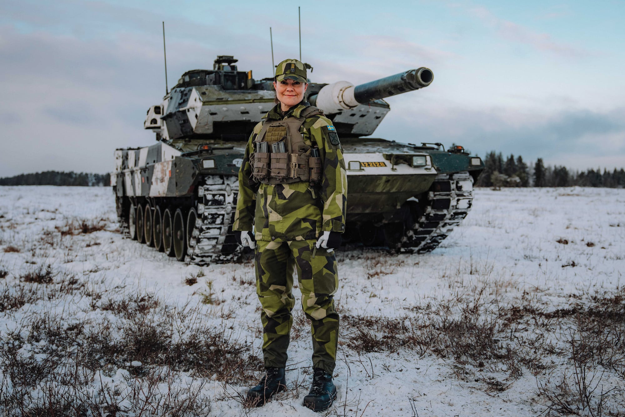 Con uniforme de faena, posa frente a un tanque