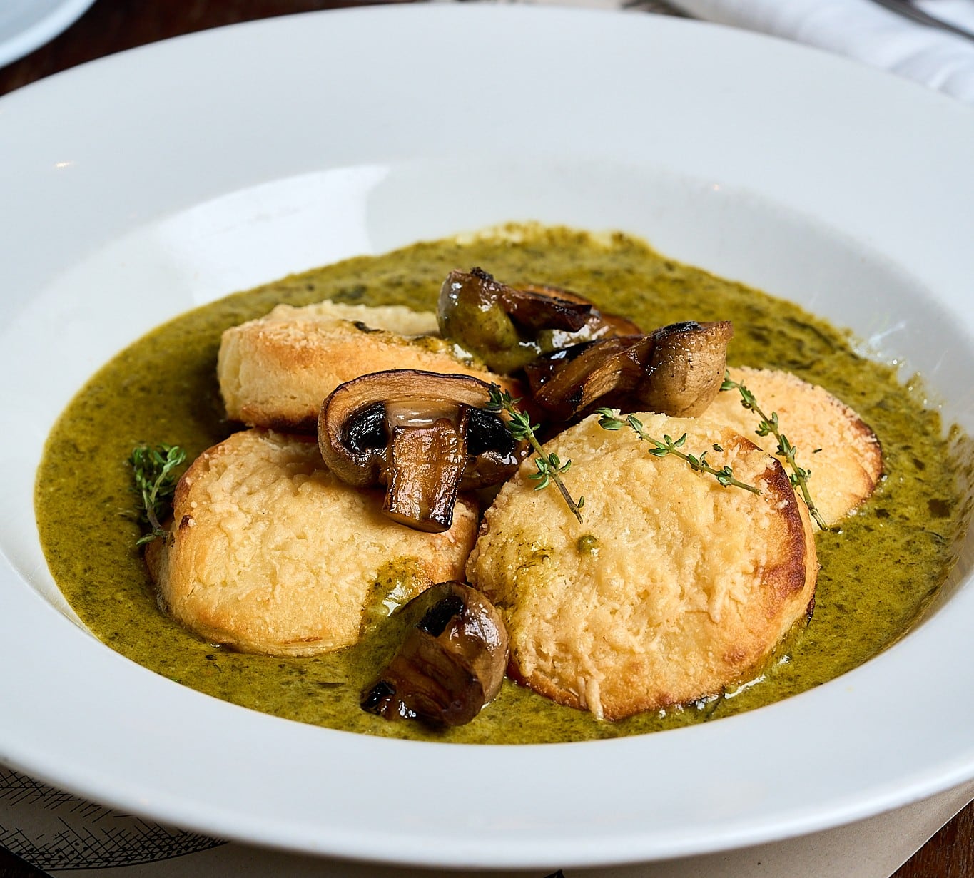Ñoquis de sémola a la romana, preparados con sémola de grano duro, leche, manteca, parmesano y nuez moscada de Granero; se sirven con crema de espinaca y hongos frescos