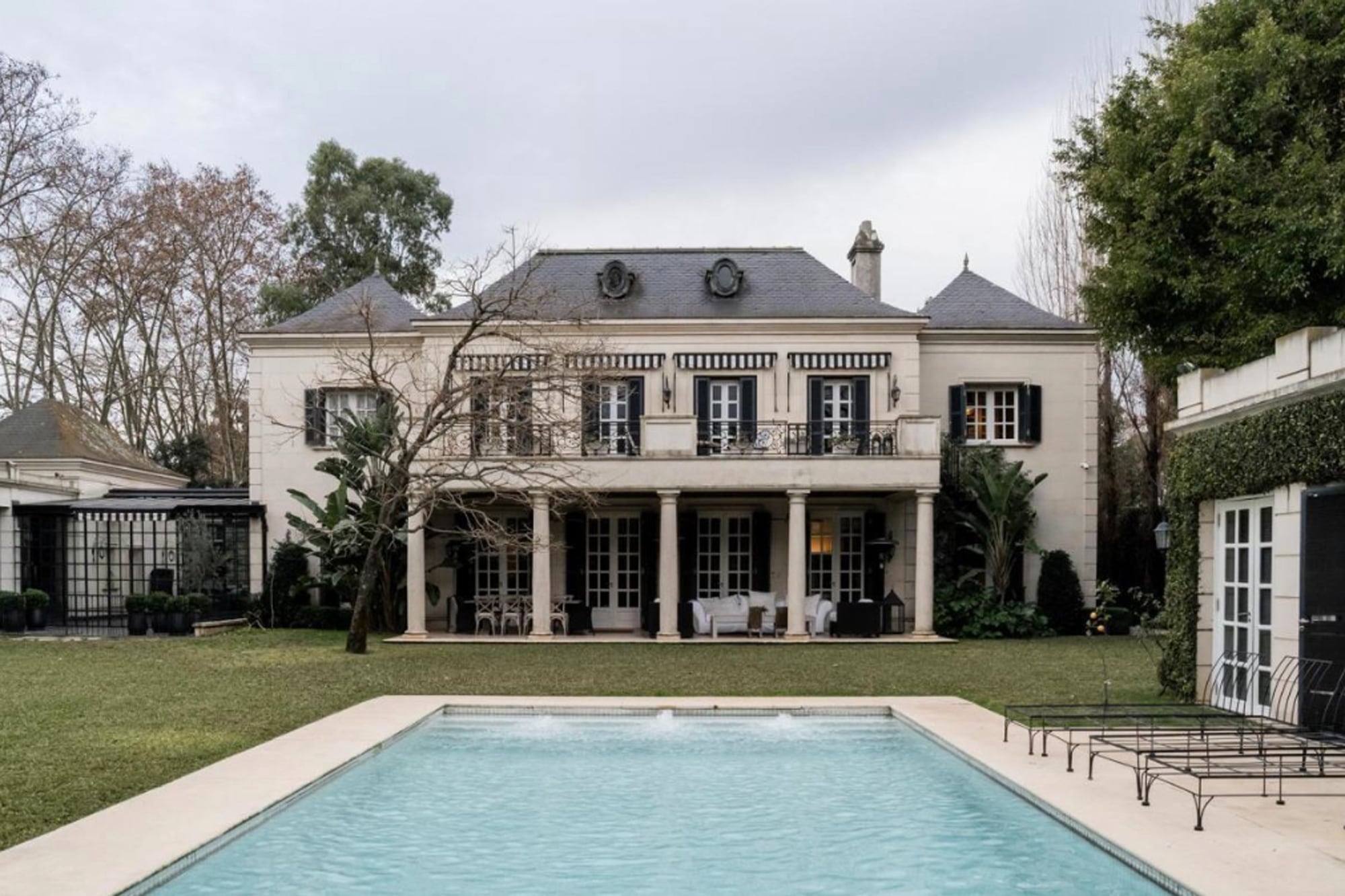 La casa tiene una impronta clásica francesa, con fachada simétrica, cipreses, molduras en piedra y doble puerta de entrada