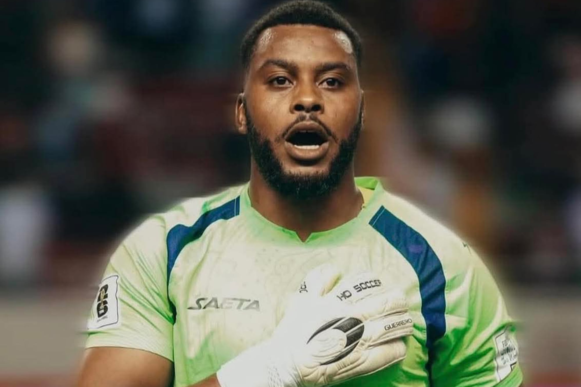 Josué Duverger, arquero de Haití, con la mano en su corazón y sobre el escudo de la Federación de Haití: en medio de una crisis muy grande, la emoción correrá en cada haitiano.