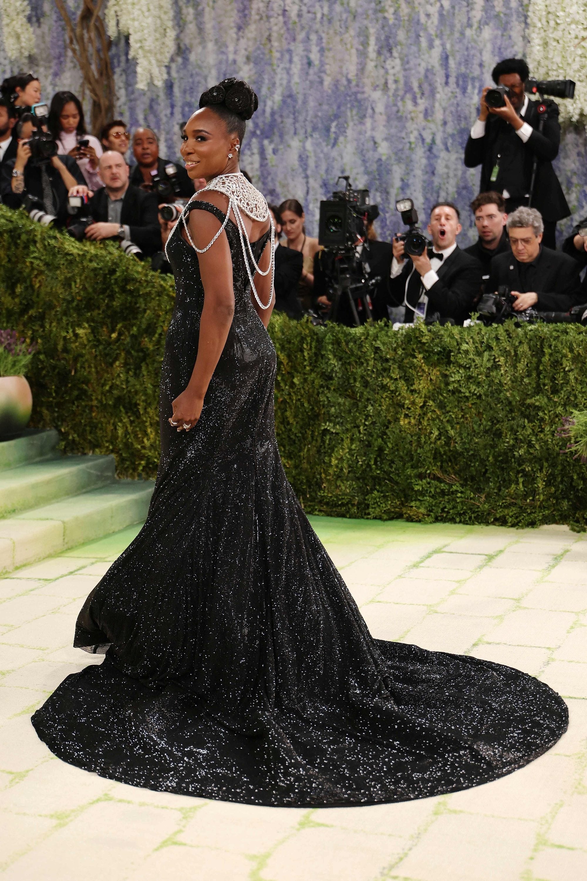 Venus Williams, otra de la copresidentas de esta edición 2026, luce majestuosa con este deslumbrante vestido con brillos y un collar plateado de Swarovski, inspirado en un retrato suyo que se encuentra en la National Portrait Gallery