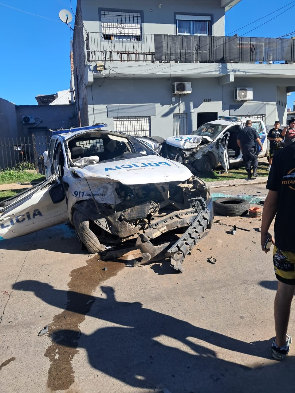 La escena del choque con personal policial y vecinos en la vereda; restos de piezas sobre el asfalto