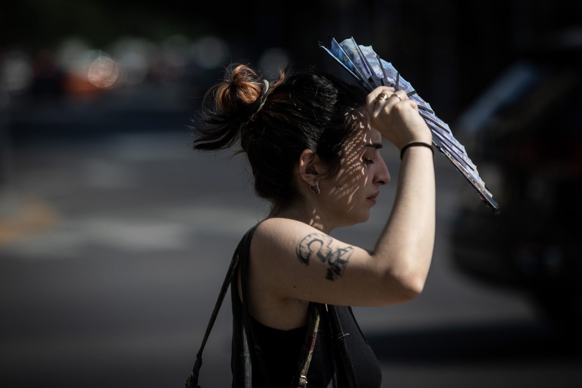 Una mujer se cubre el sol con un abanico durante la ola de calor en la ciudad de Buenos Aires