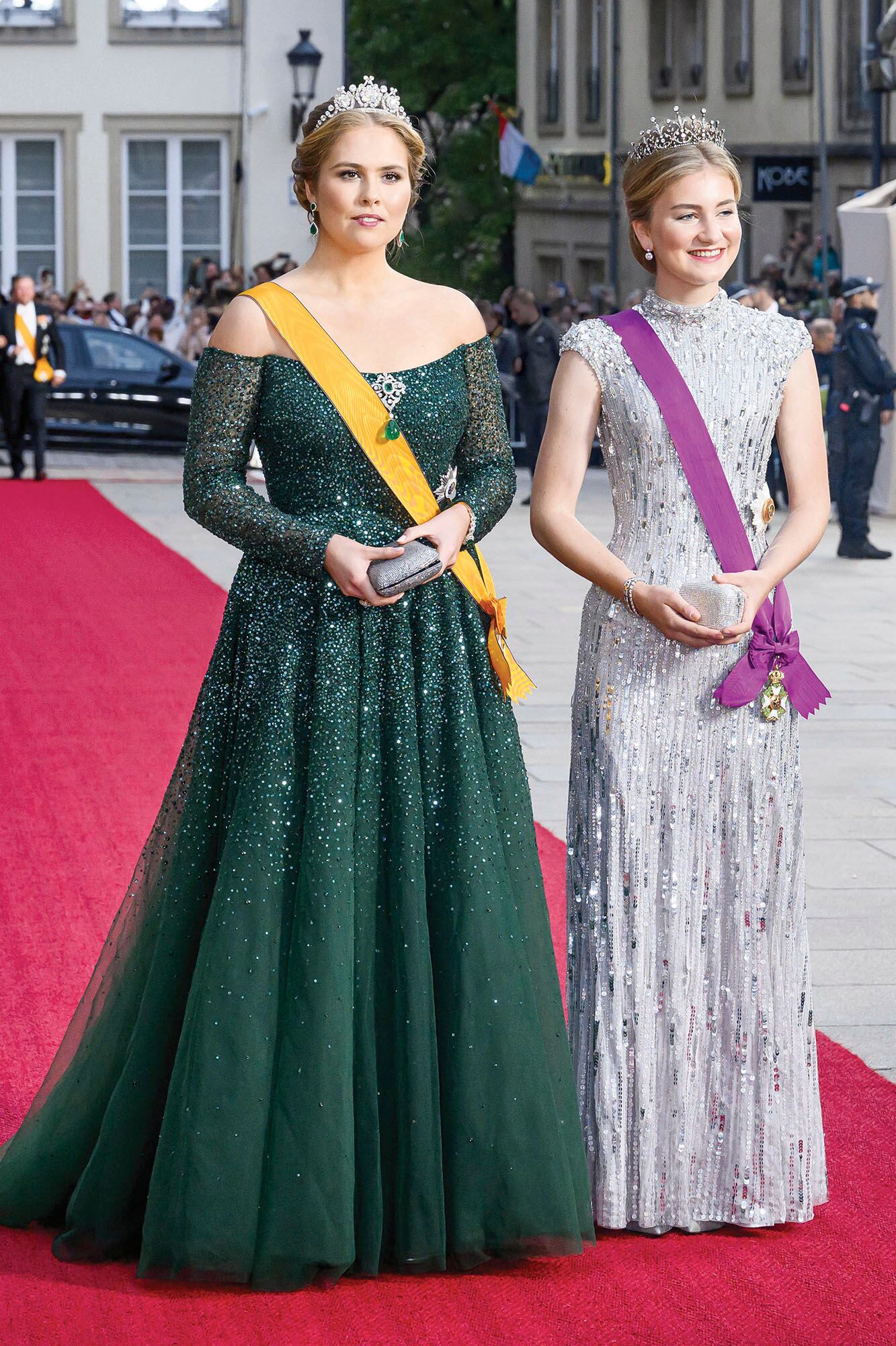 Las princesas herederas de Países Bajos y Bélgica ocuparon un lugar especial en cada uno de los actos y, a su llegada a la comida de gala, fueron ovacionadas. Para esa ocasión, Amalia eligió un vestido de Monique Lhuillier en color verde, con cristales y lentejuelas, pronunciado escote en V, falda de tul en línea trapecio y ceñido a la cintura, perfecto para lucirlo con la tiara de la reina Emma. Elisabeth, por su parte, apostó por un diseño plateado de Jenny Packham cubierto de lentejuelas, que potenció con la tiara de diamantes que sus padres le regalaron para su cumpleaños número 18