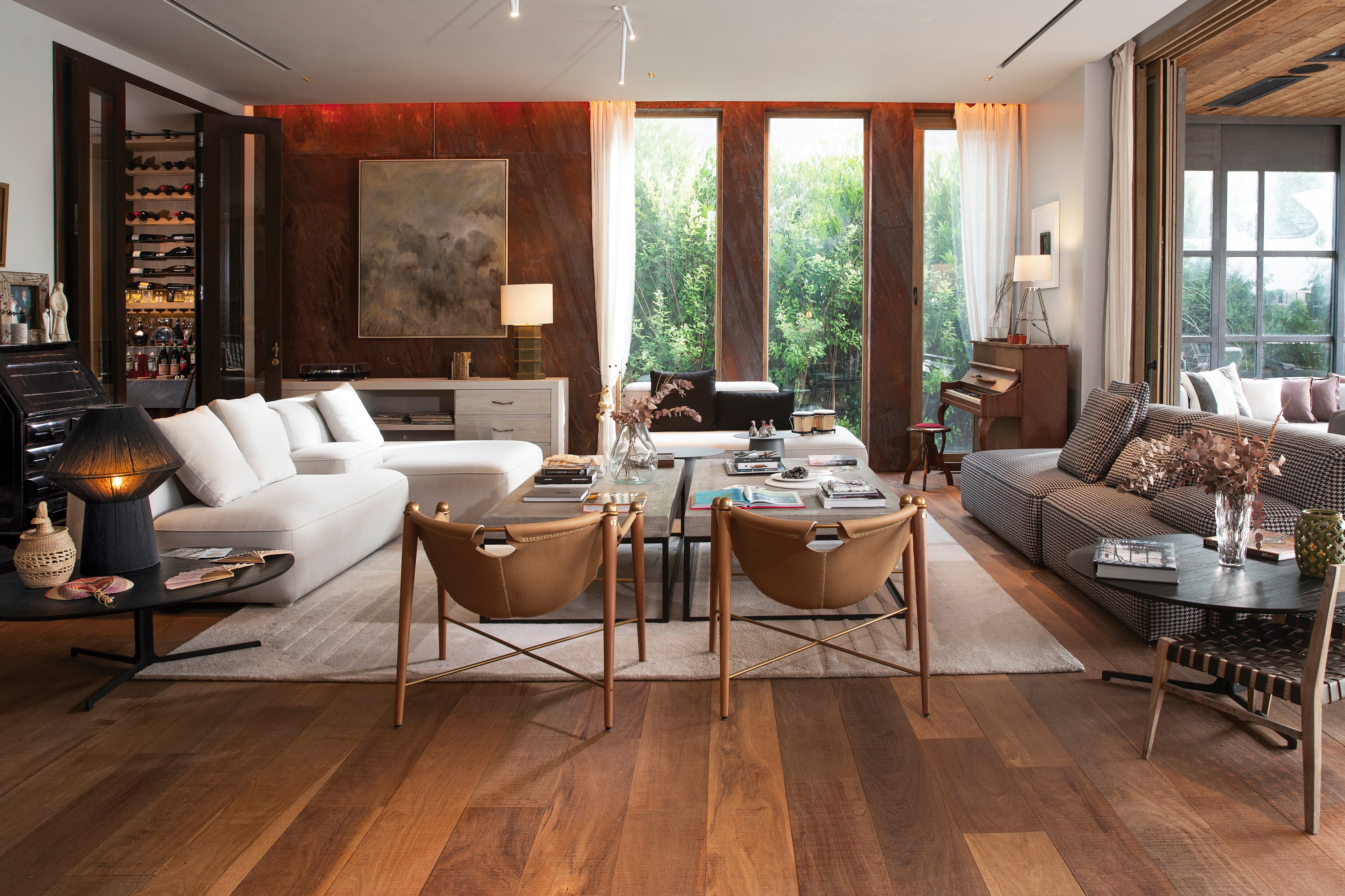 El living tiene diferentes spots, como el del piano, el de los vinilos, donde se destaca una pared revestida en piedra bronzite rugoso. Los ventanales, que se abren de punta a punta, logran un espectacular efecto in/out