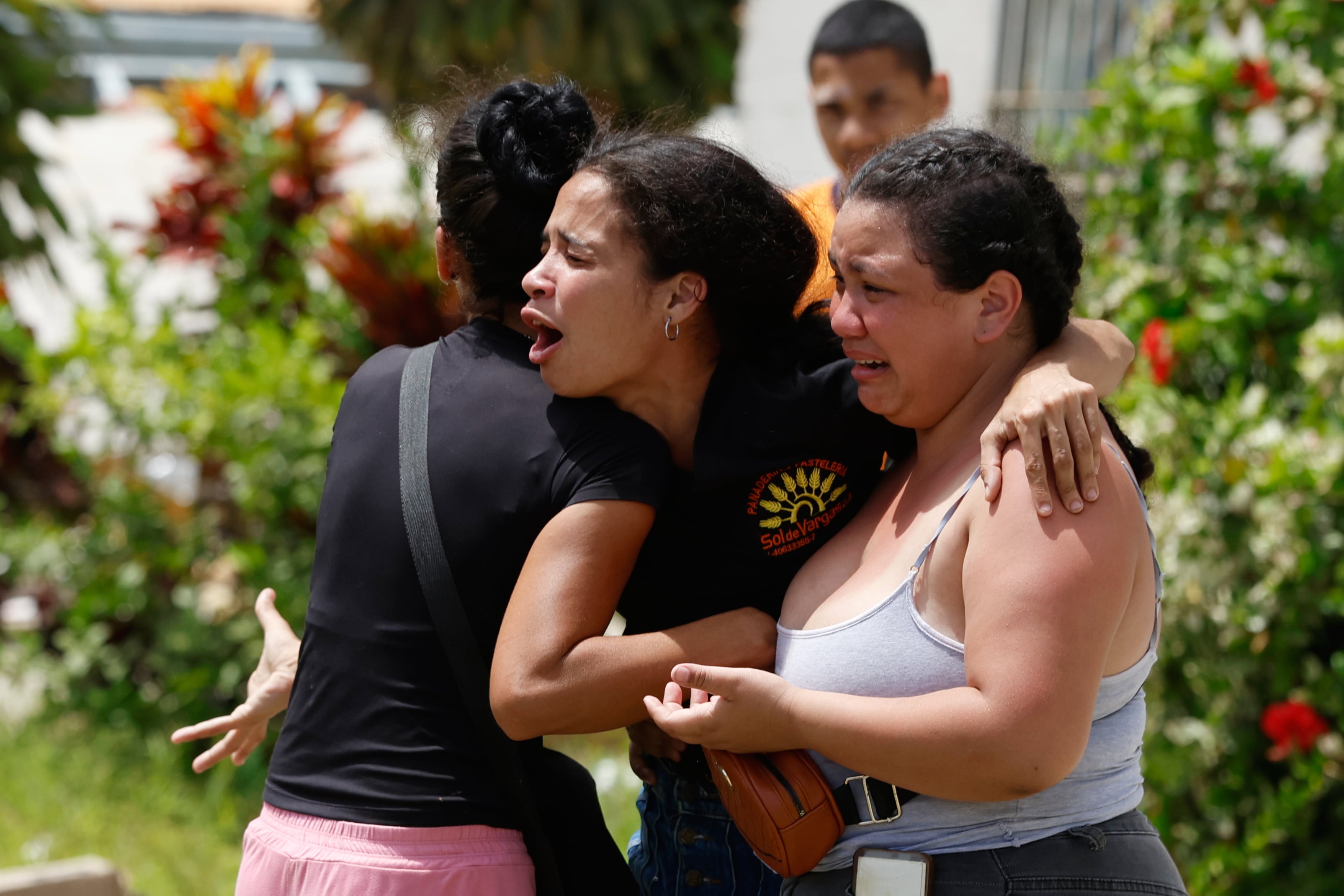 Personas consuelan a Gabriela Rojas, en el centro, mientras llora frente a su casa dañada, donde dos de sus hijos fallecieron durante los terremotos que sacudieron La Guaira