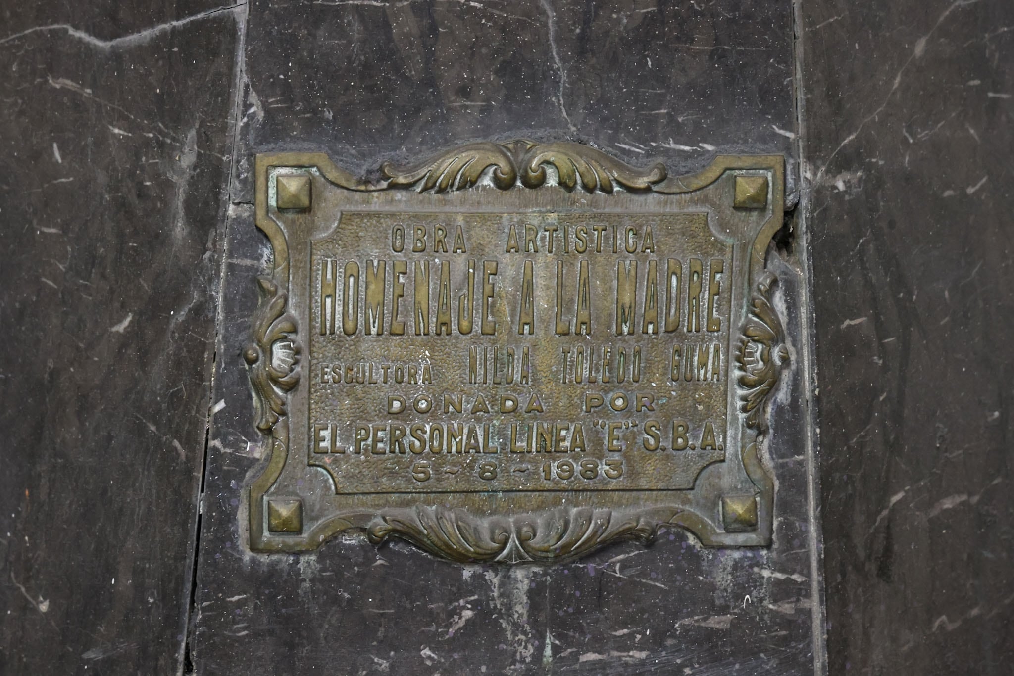 La placa de la obra de Toledo Guma fue donada por el personal de la Línea E de subtes en 1983; se ven grietas en la base