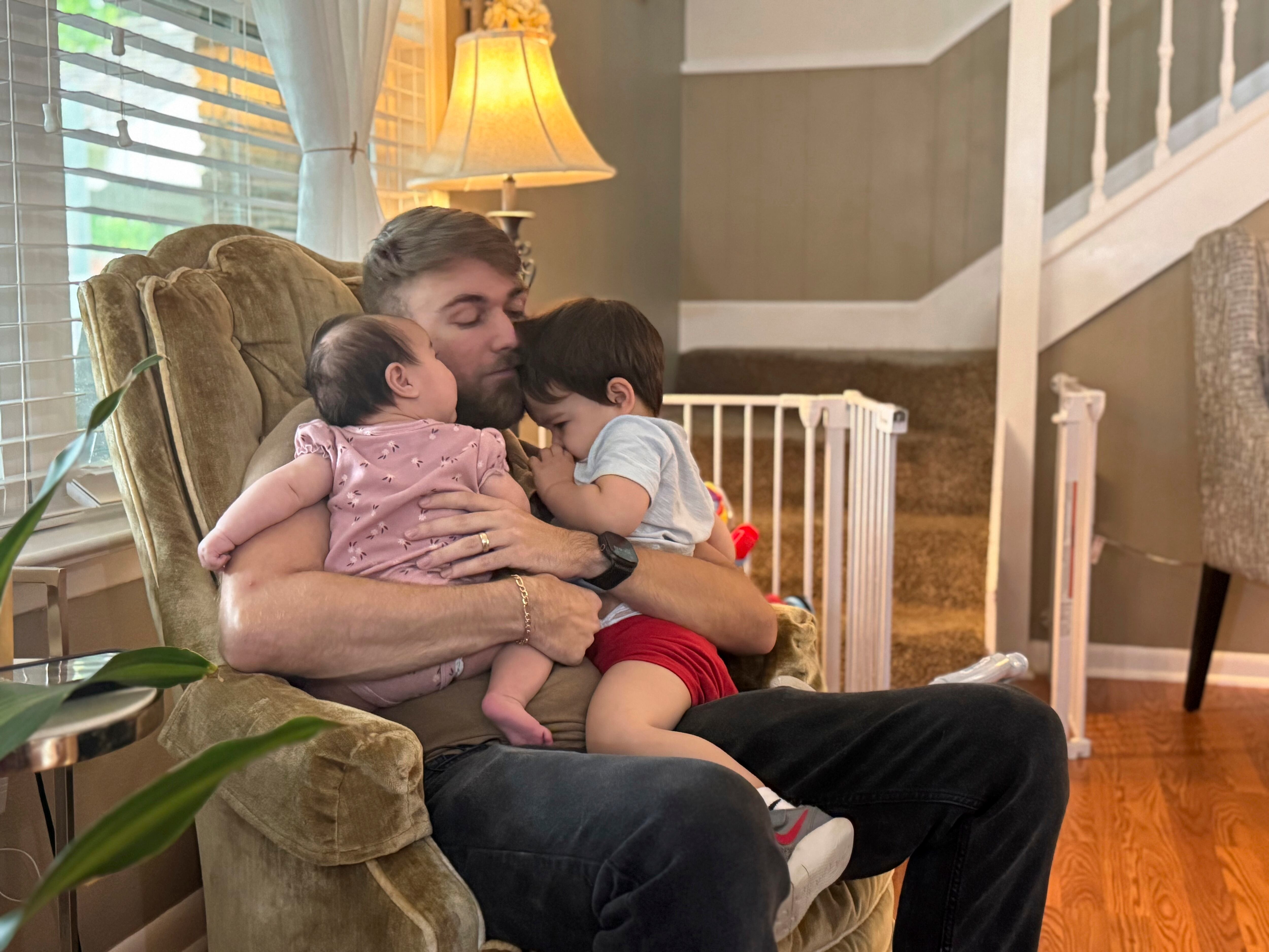 El veterano del Cuerpo de Marines de Estados Unidos, Adrian Clouatre, carga a su hija de 3 meses de edad, Lyn, y a su hijo de casi 2 años de edad, Noah, en su residencia, el 17 de junio de 2025, en Baton Rouge, Luisiana. (AP Foto/Stephen Smith, Archivo)
