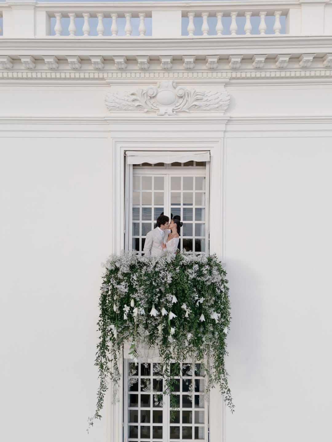 Los recién casados se funden en un beso de película en uno de los balcones decorado flores blancas