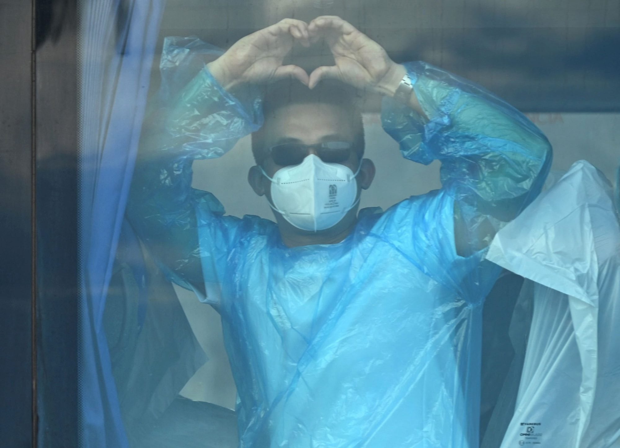 Pasajeros del crucero MV Hondius, afectado por el hantavirus, hacen un gesto desde un autobús militar tras desembarcar en el puerto de Granadilla de Abona, en la isla de Tenerife