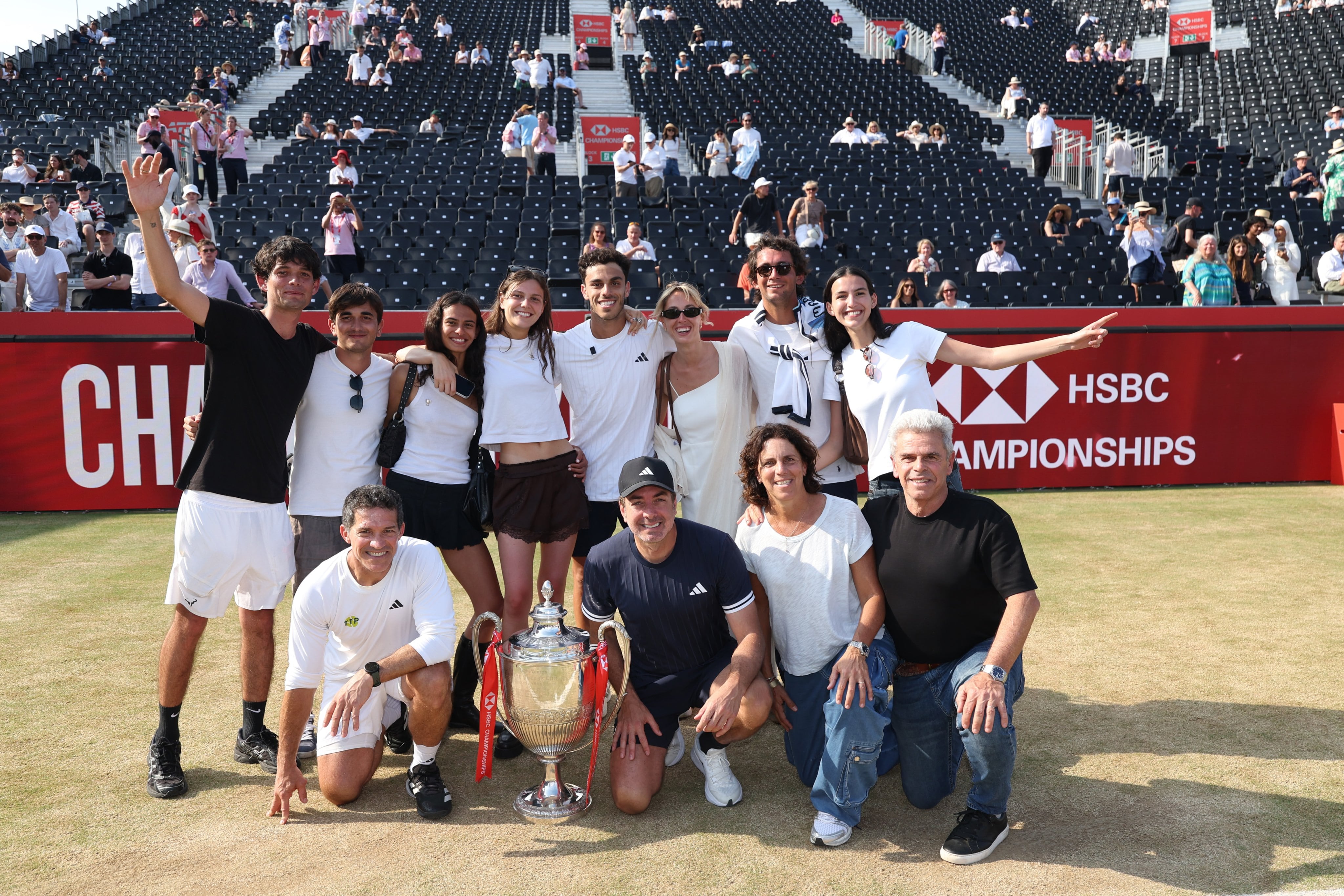 Padres, equipo (entre ellos, el nuevo coach, Nicolás Massú) y allegados de Francisco Cerúndolo, posando con el trofeo del ATP 500 de Queen's