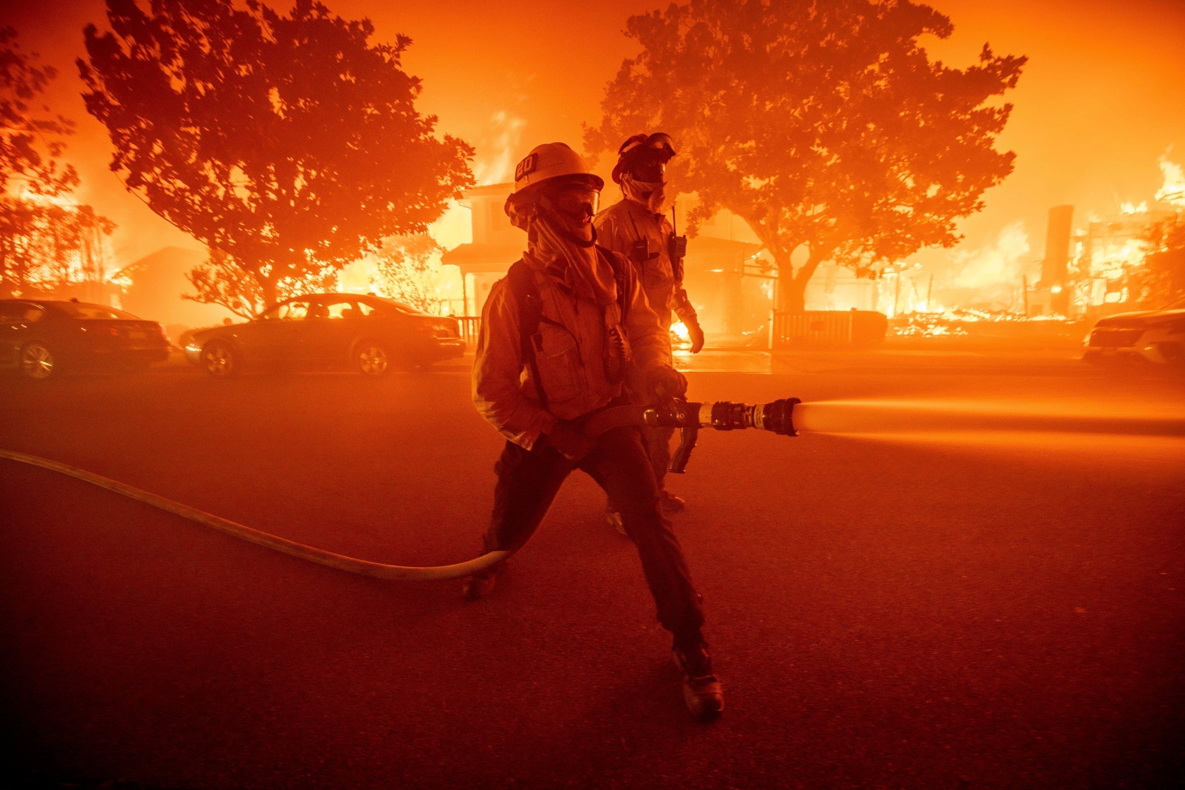 ARCHIVO - Dos bomberos combaten un incendio en el vecindario Pacific Palisades, el martes 7 de enero de 2025, en Los Ángeles. (AP Foto/Ethan Swope, archivo)