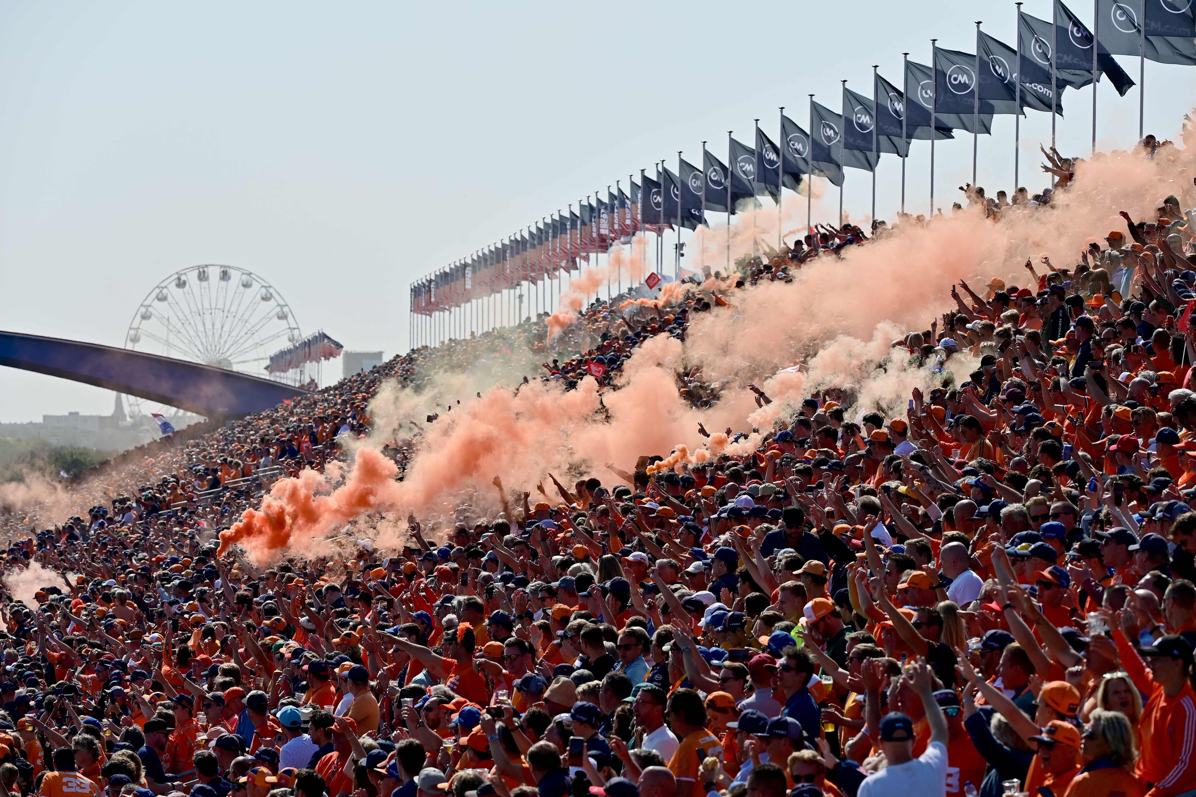 (FILES) Fans burn orange flares during the drivers' parade at the Zandvoort circuit before the start of the Netherlands' Formula One Grand Prix in Zandvoort on September 5, 2021. For three days a year, the quiet residential street of Van Speijkstraat in the sleepy Dutch beach resort of Zandvoort transforms itself into a sea of orange streamers and chequered flags, welcoming Formula One fans from around the world. (Photo by ANDREJ ISAKOVIC / AFP)