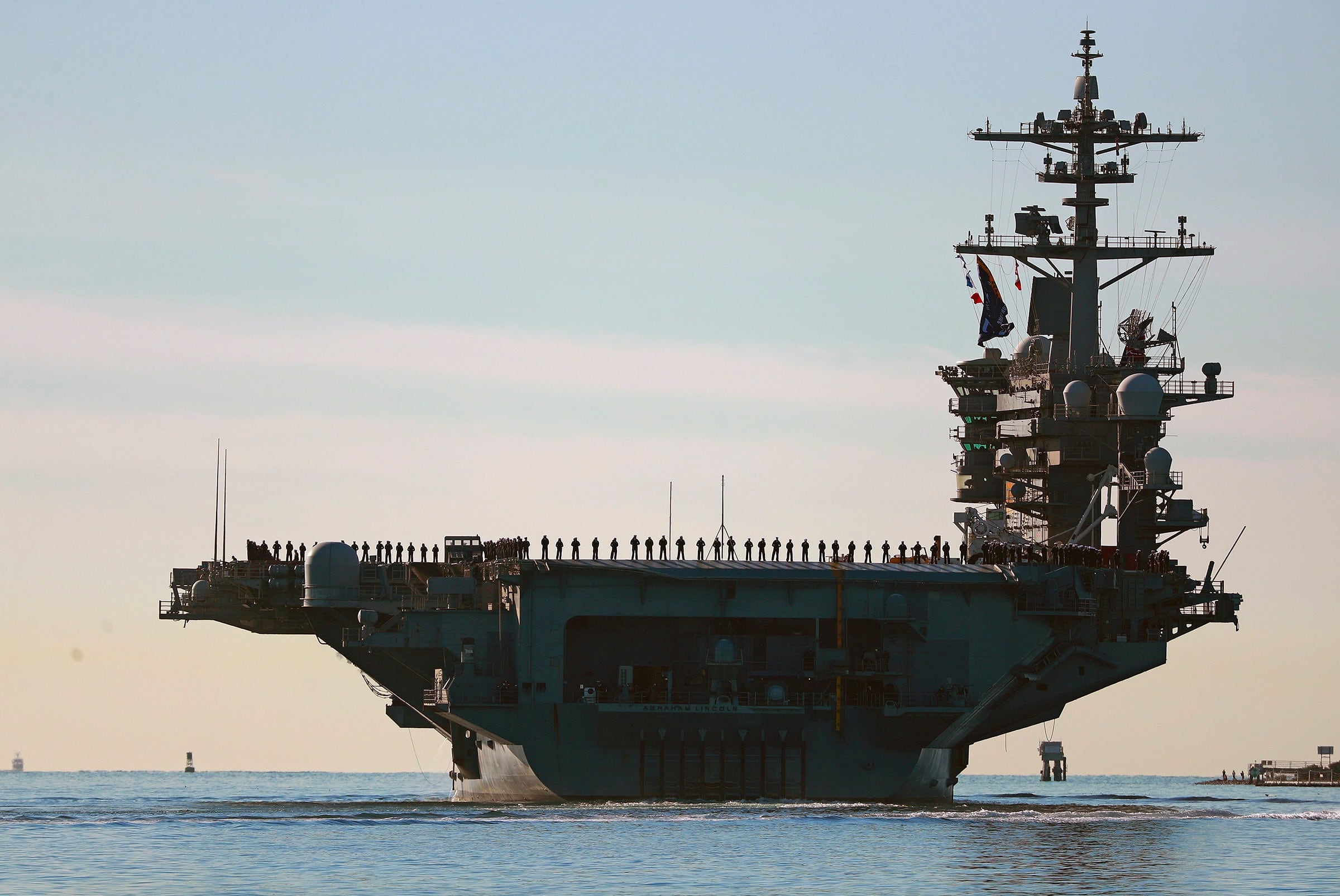 Marineros y marines se ven formados en la cubierta del portaviones USS Abraham Lincoln