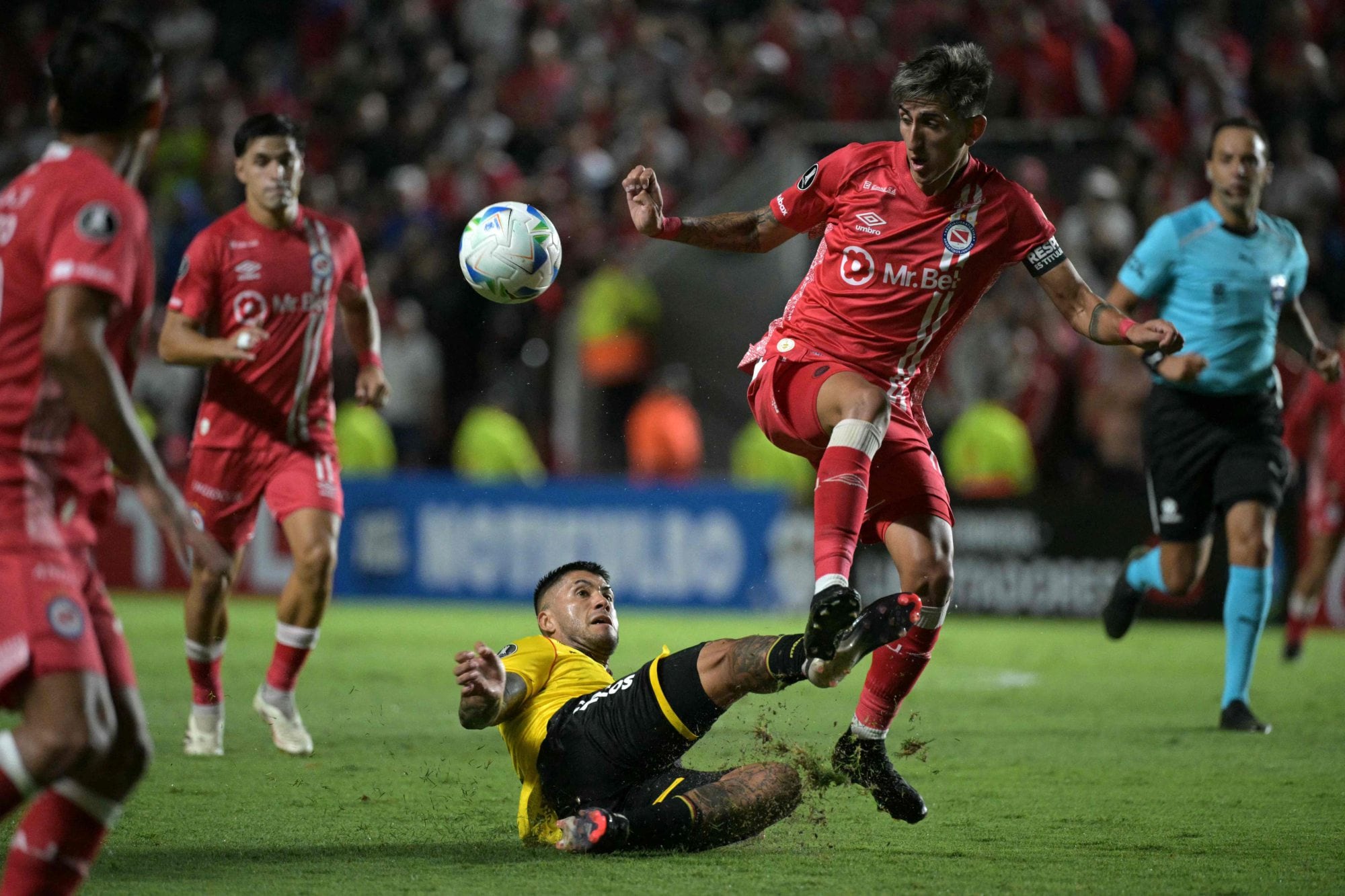 Milton Céliz, desde el piso, le saca la pelota a Alan Lescano; el exvolante de Riestra fue uno de los destacados en la visita (Photo by JUAN MABROMATA / AFP)