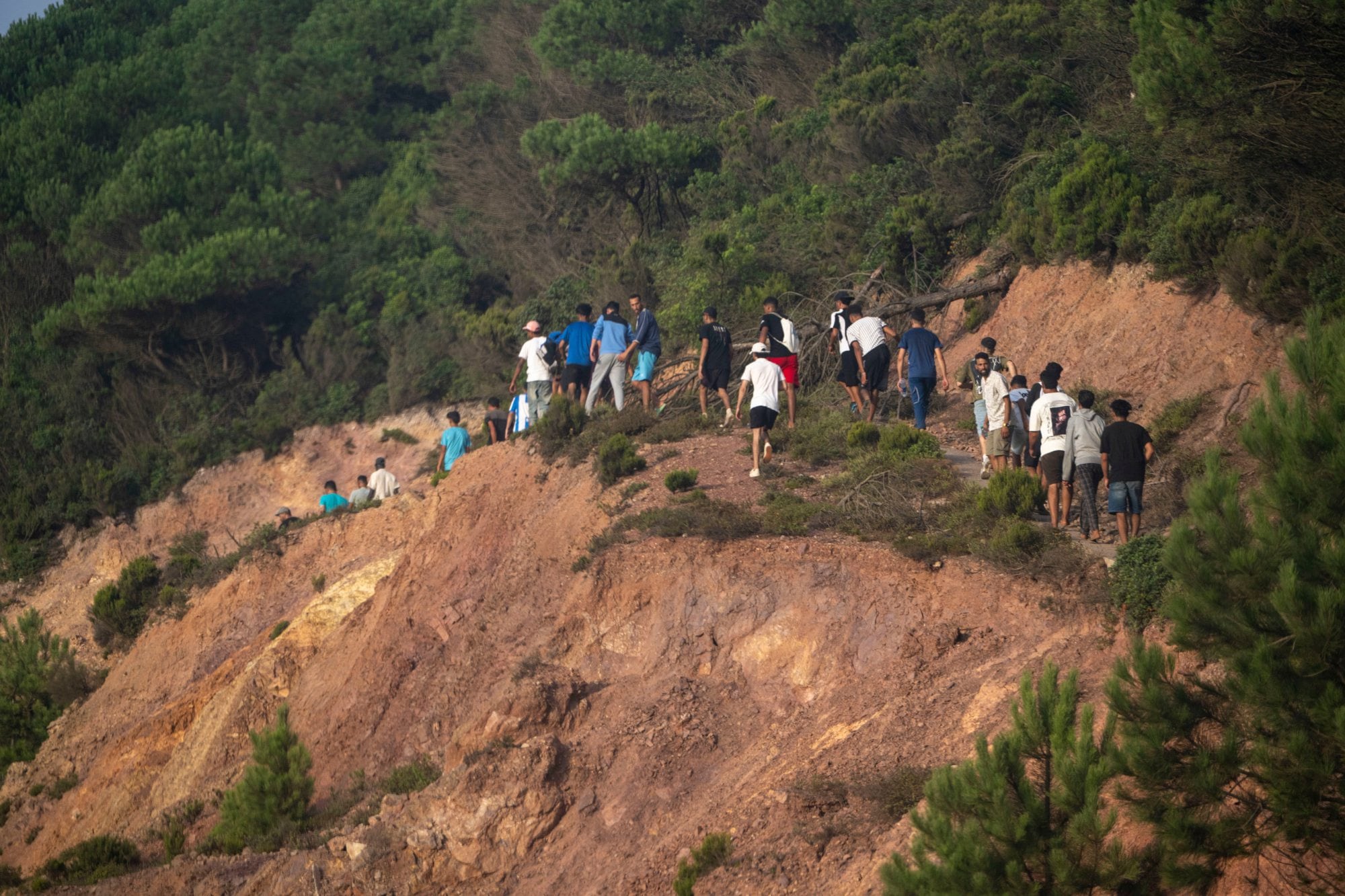 Migrantes marroquíes atraviesan una zona escarpada en la divisoria entre Marruecos y Ceuta